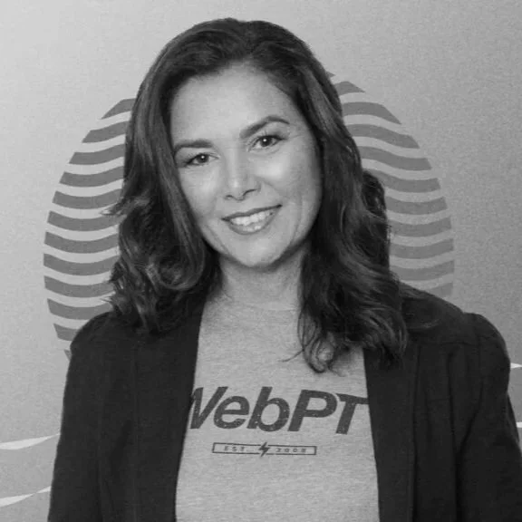 A woman with wavy hair wearing a WebPT t-shirt and a dark jacket, smiling at the camera in front of a logo background.