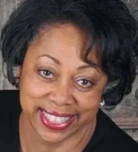 Close-up of a woman with dark hair and a bright smile.