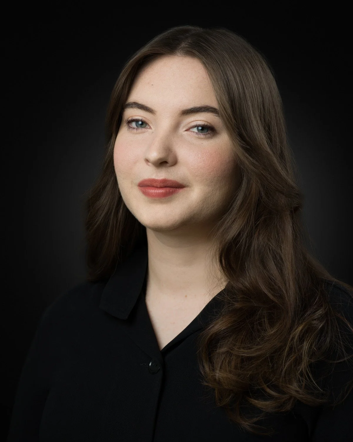 Commercial headshot of Skyela Jones with a direct, captivating gaze and a 'knowing' glimmer. Her expression is warm and accessible, suggesting an intelligent character with a secret and a grounded, sophisticated charm.
