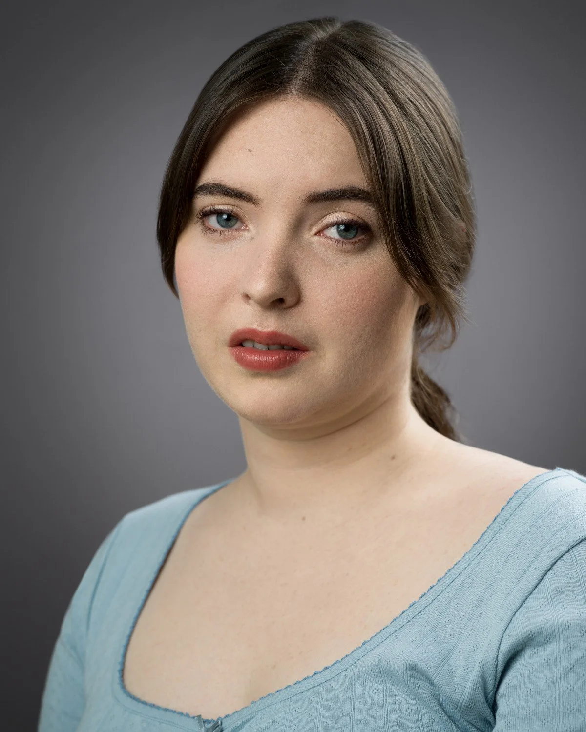 Theatrical headshot of Skyela Jones in a soft blue top; her expression is evocative and raw. With a searching gaze and a hint of vulnerability, she conveys a character of deep emotional sensitivity. Period dramas & high-stakes victim or witness roles