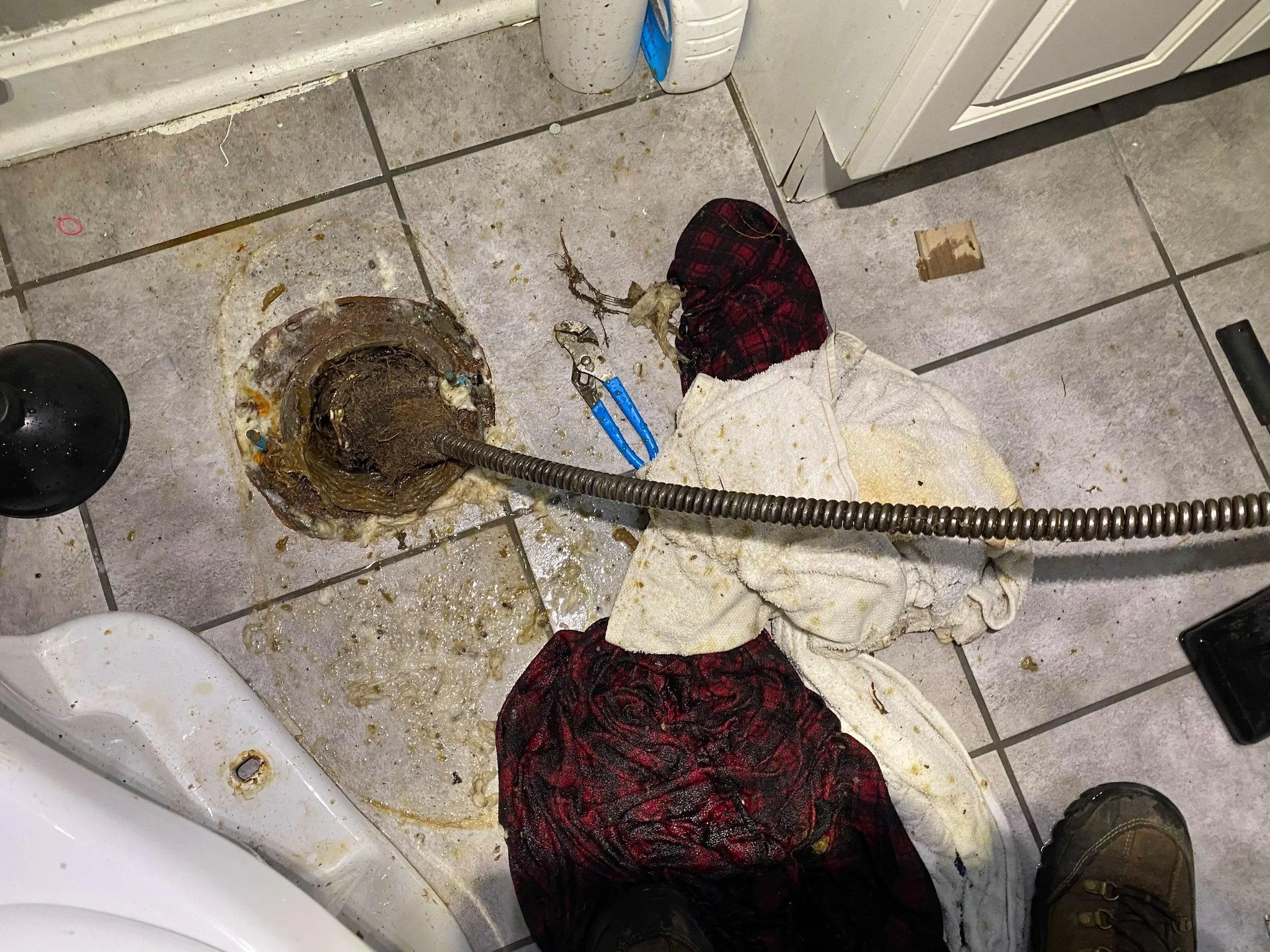 Unclogging bathroom toilet with sewer rod.