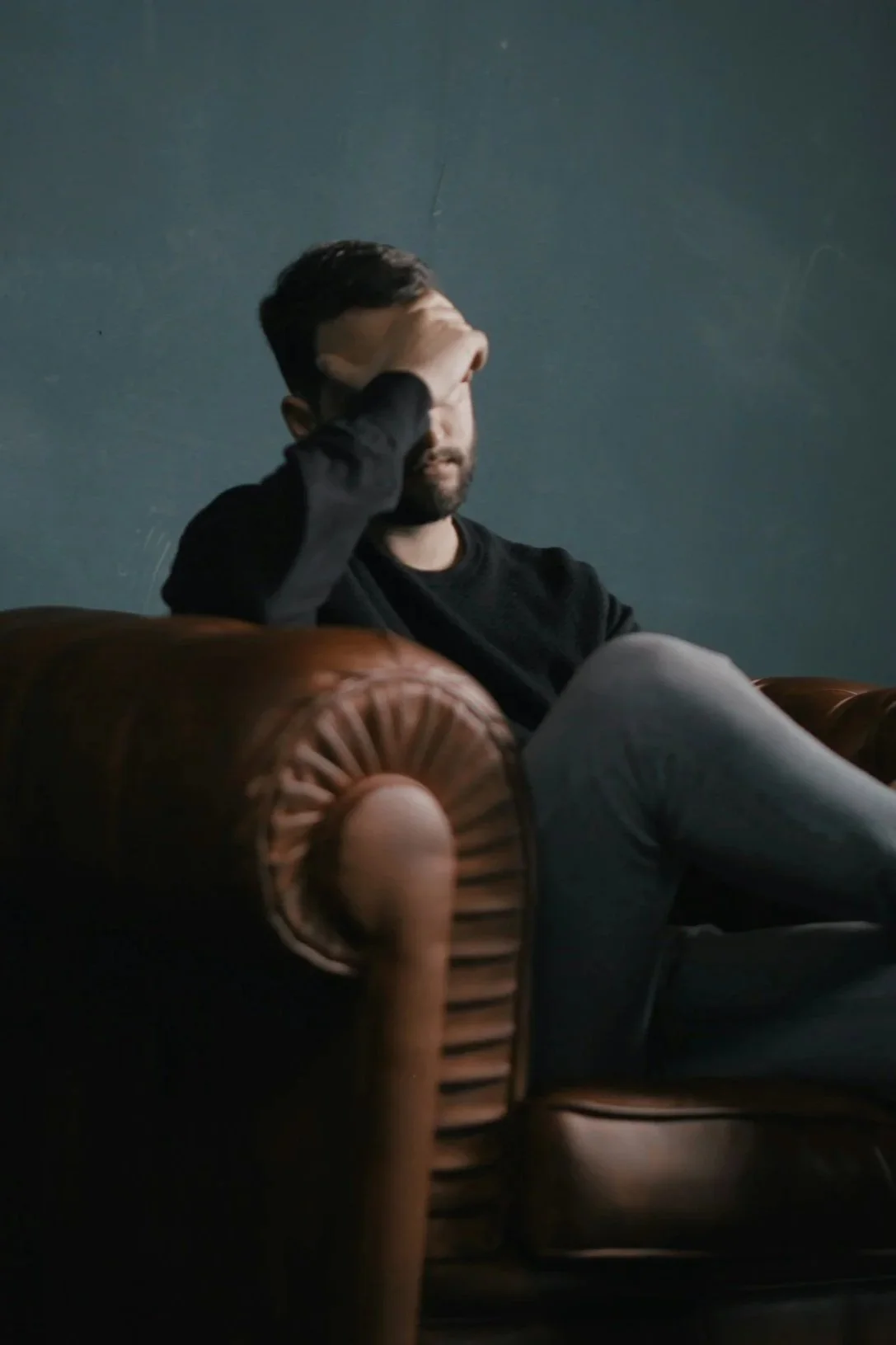 man sitting in chair with hand over his eyes