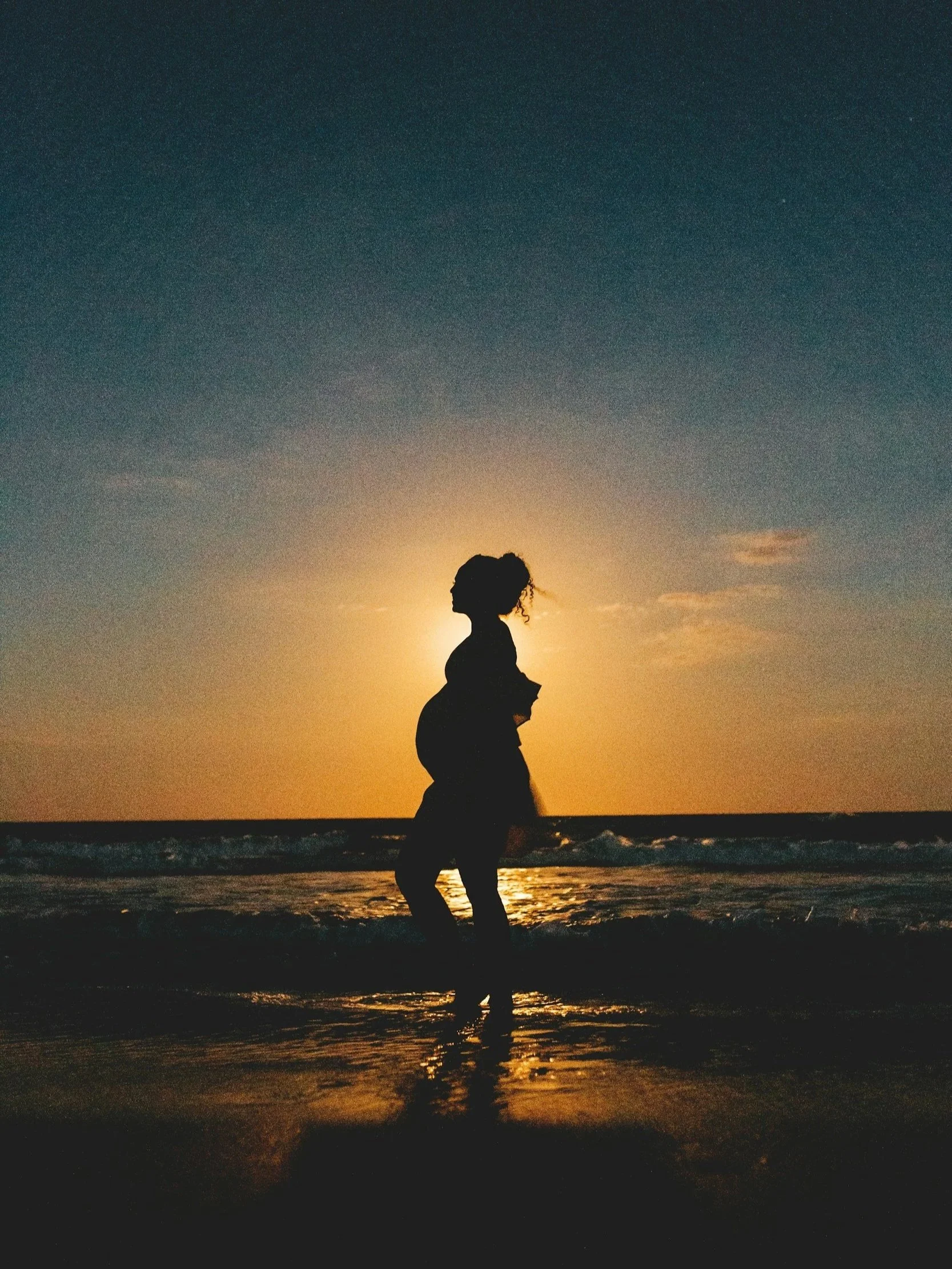 silhouette of pregnant woman on beach at sunset