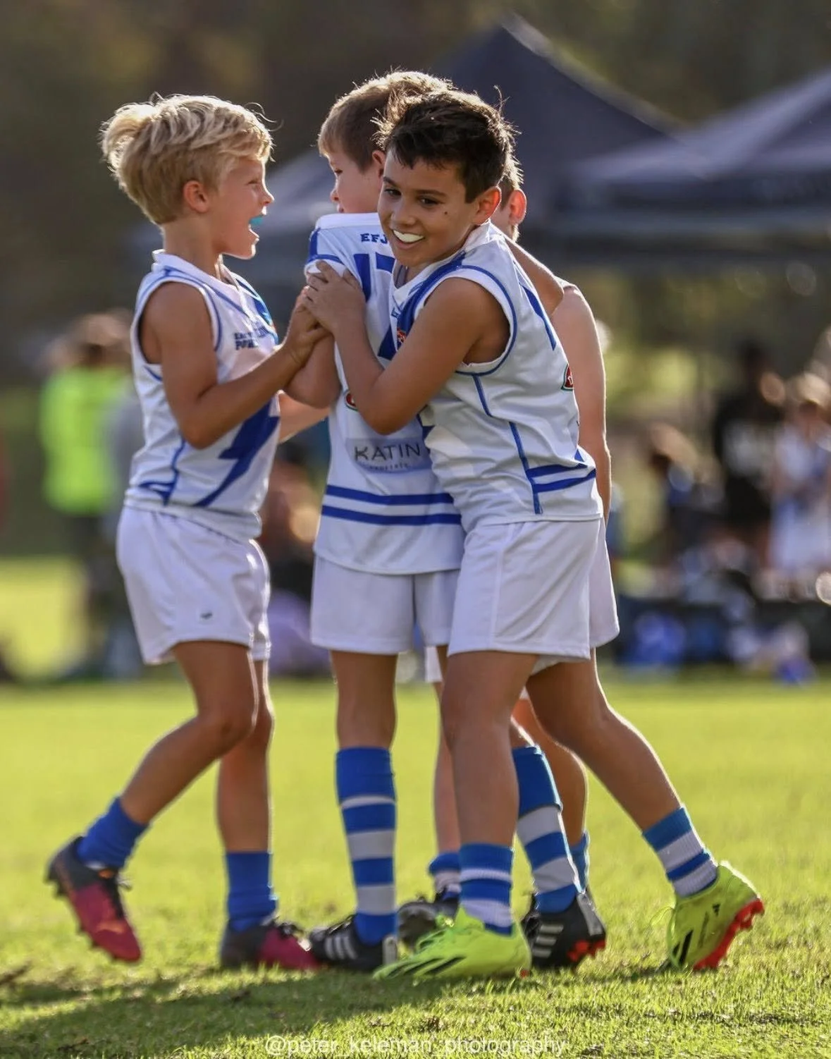 Young boys in soccer uniforms celebrating on the field.
