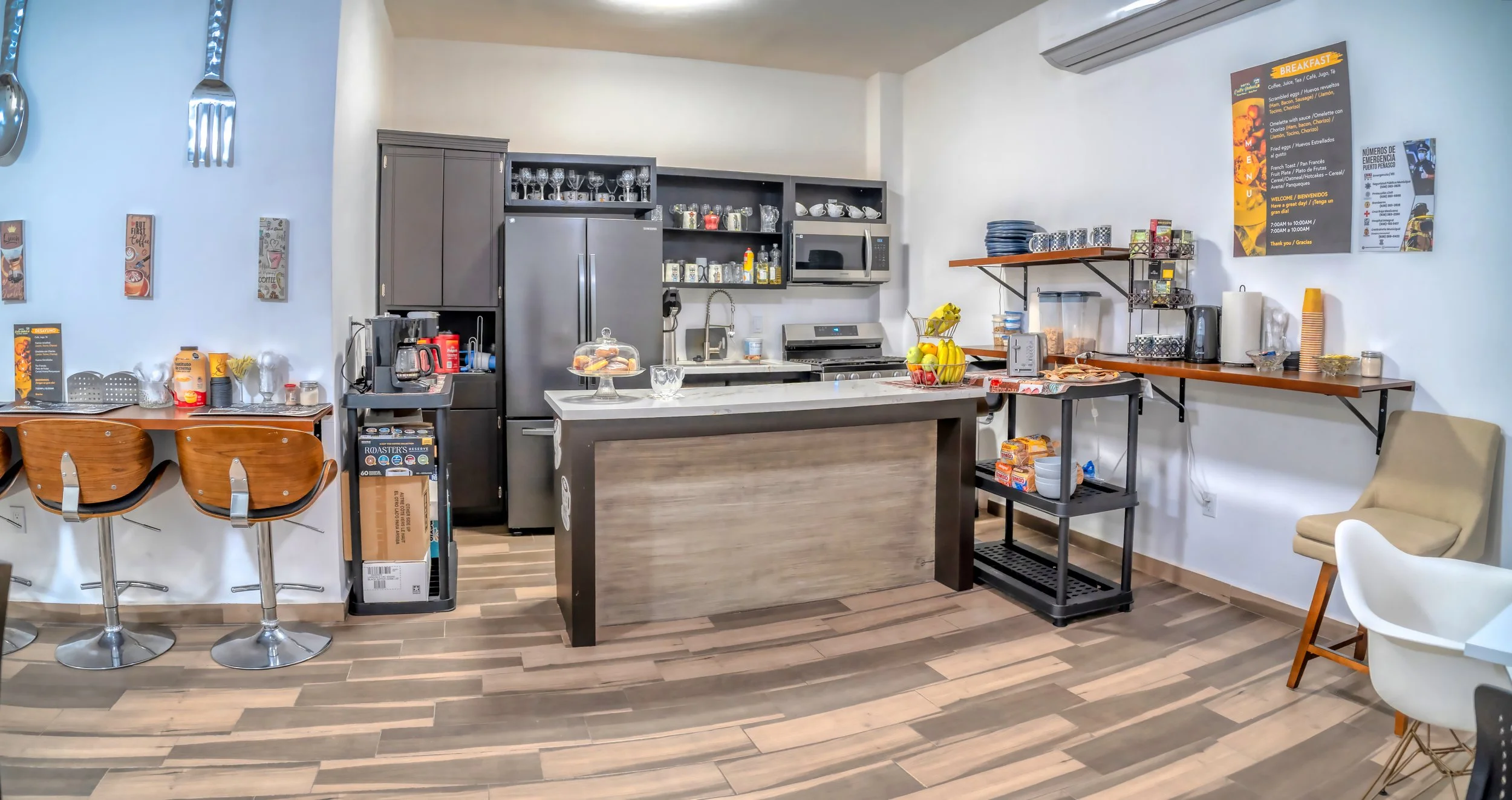 Cocina y área de comedor con electrodomésticos, estantes y sillas.