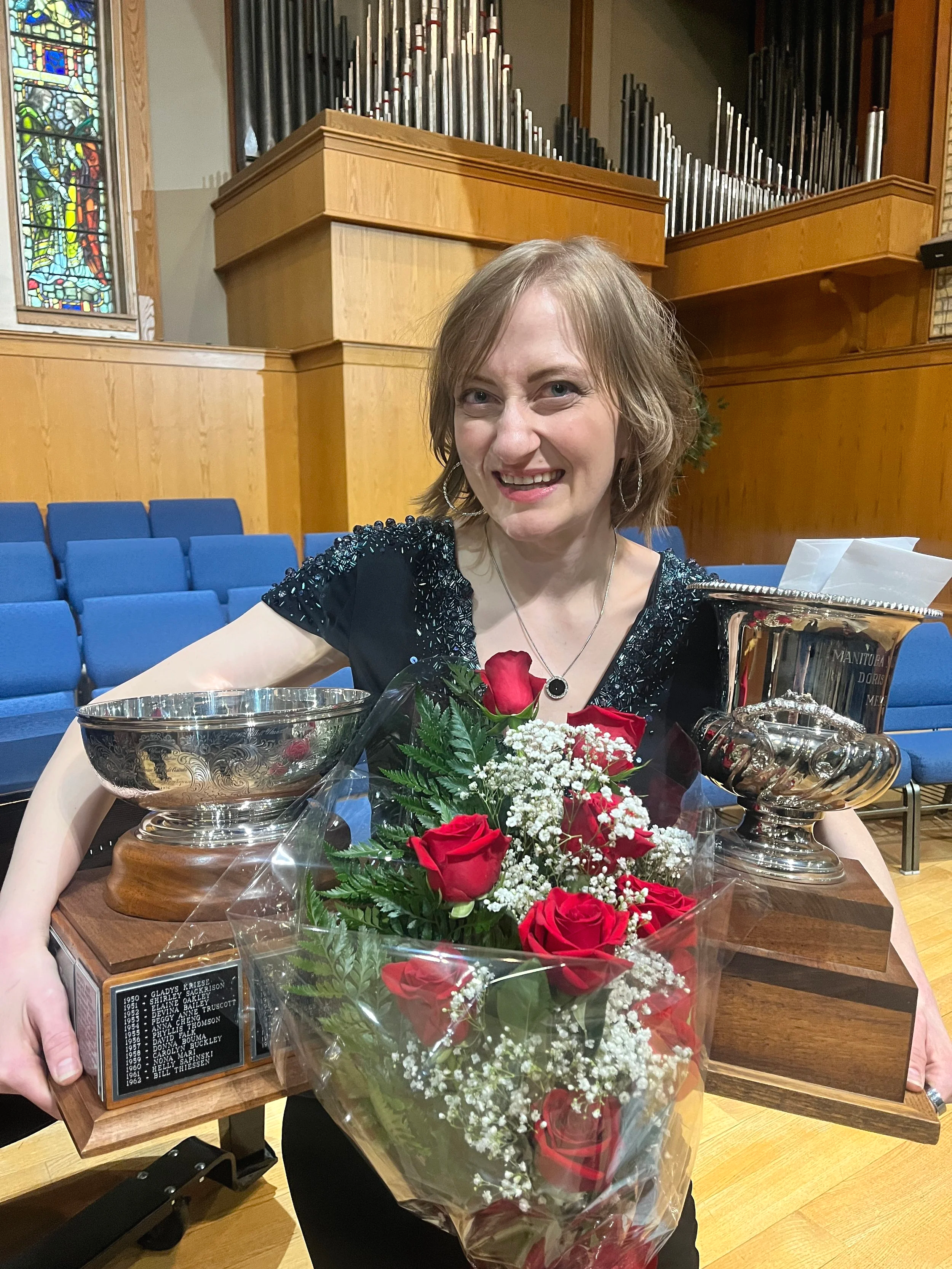 Joanna holding two trophys and roses at the Winnipeg Music Festival