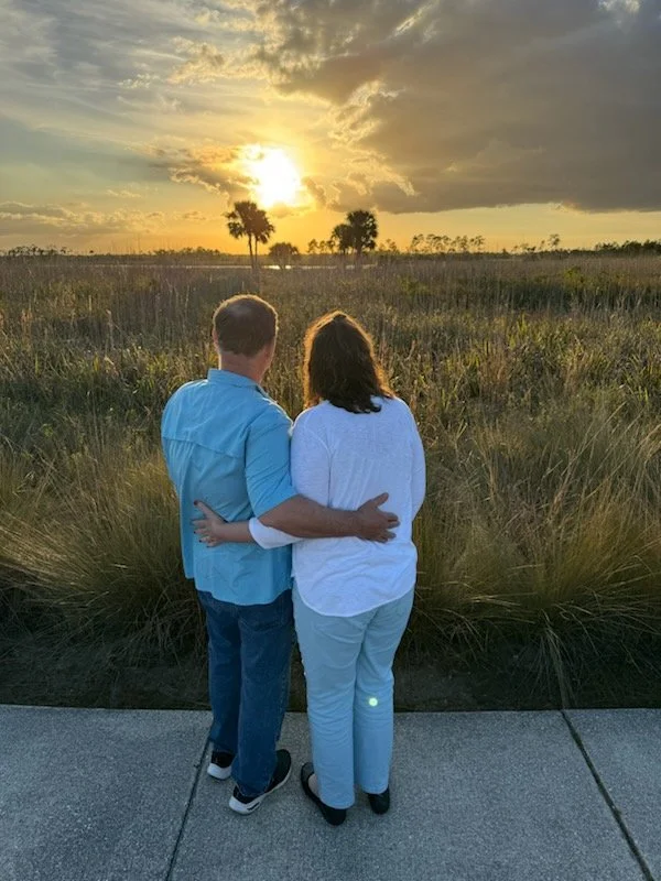A couple looking at a sunset over a field