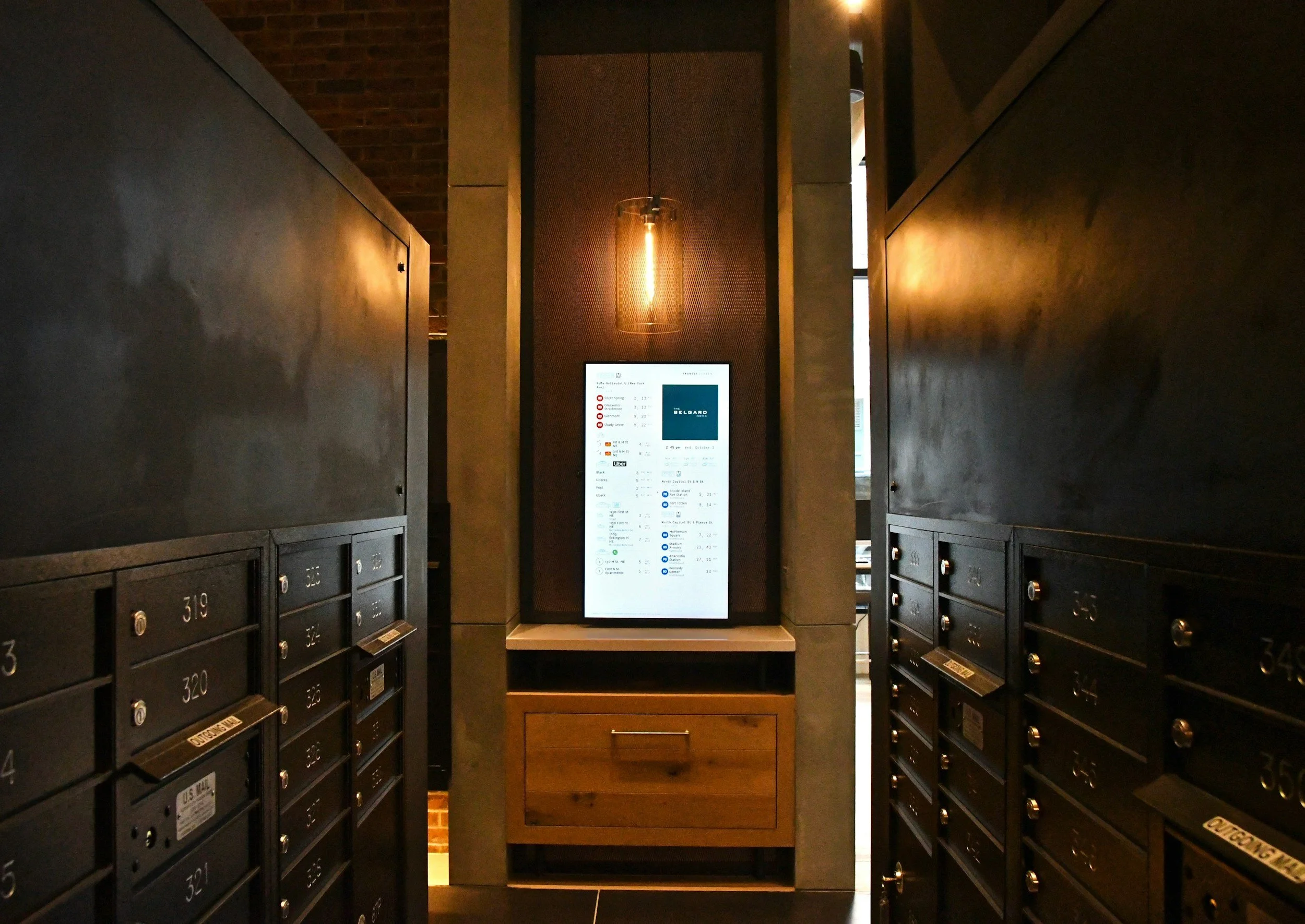 Mail lockers on both sides of a digital display in a modern lobby