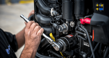 Close-up of a person using a wrench to work on a boat engine.