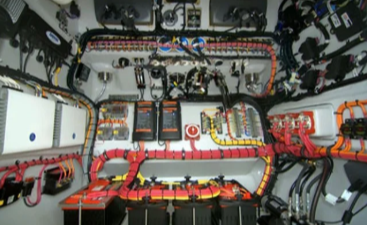 Interior view of an electrical control panel with multiple wires, circuit breakers, and interconnected components on a boat.