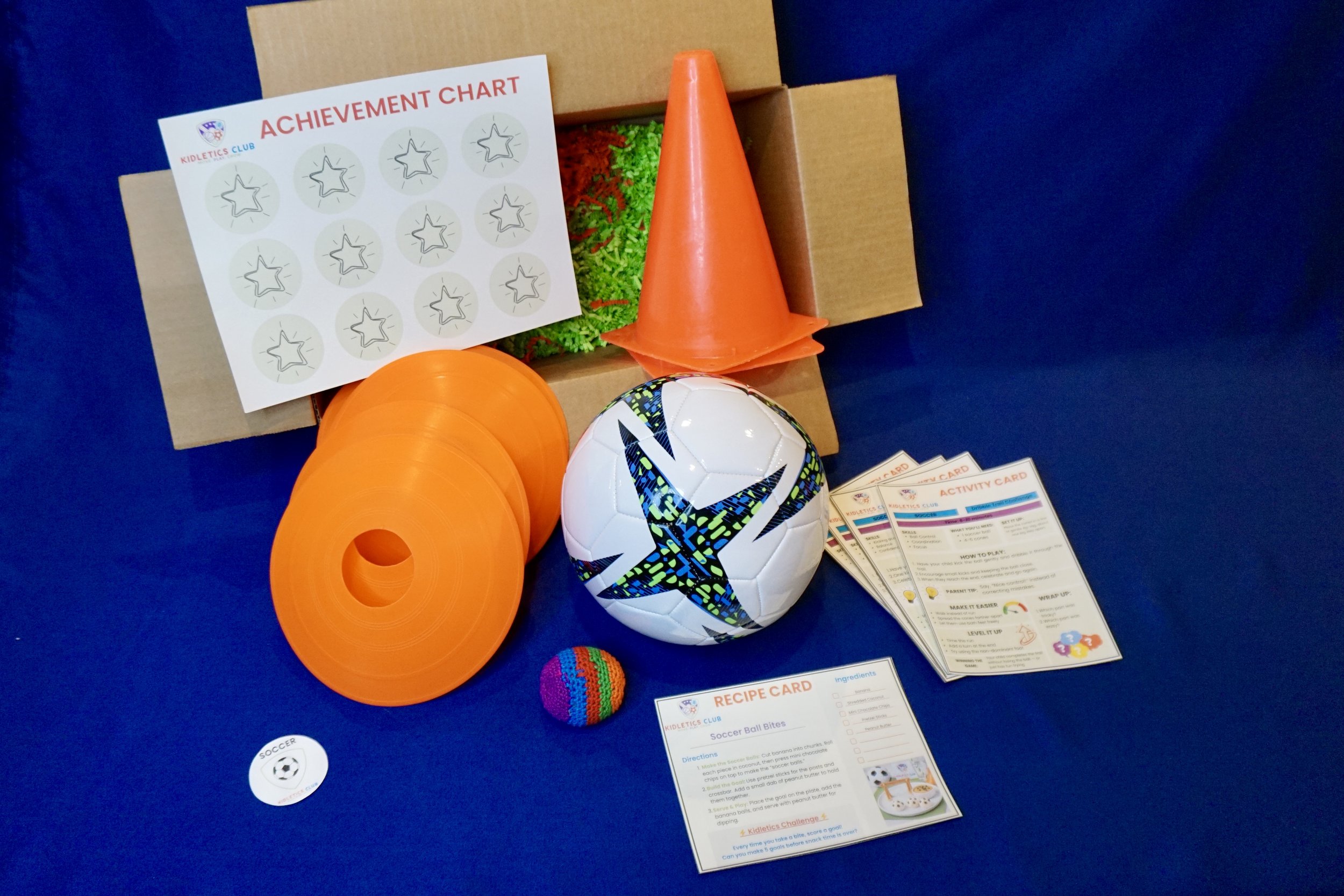 Box with sports equipment, including soccer ball, cones, and activity cards