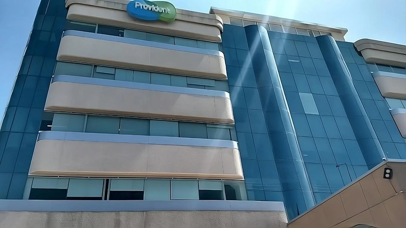 Edificio moderno con fachada de vidrio y balcones curvos, con un letrero que dice 'Provident' en la parte superior.