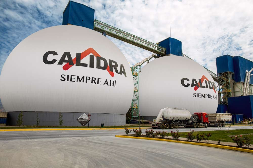 Dos tanques de almacenamiento grandes en una planta industrial con el logo de CALIDRA y la frase 'SIEMPRE AQUÍ'.