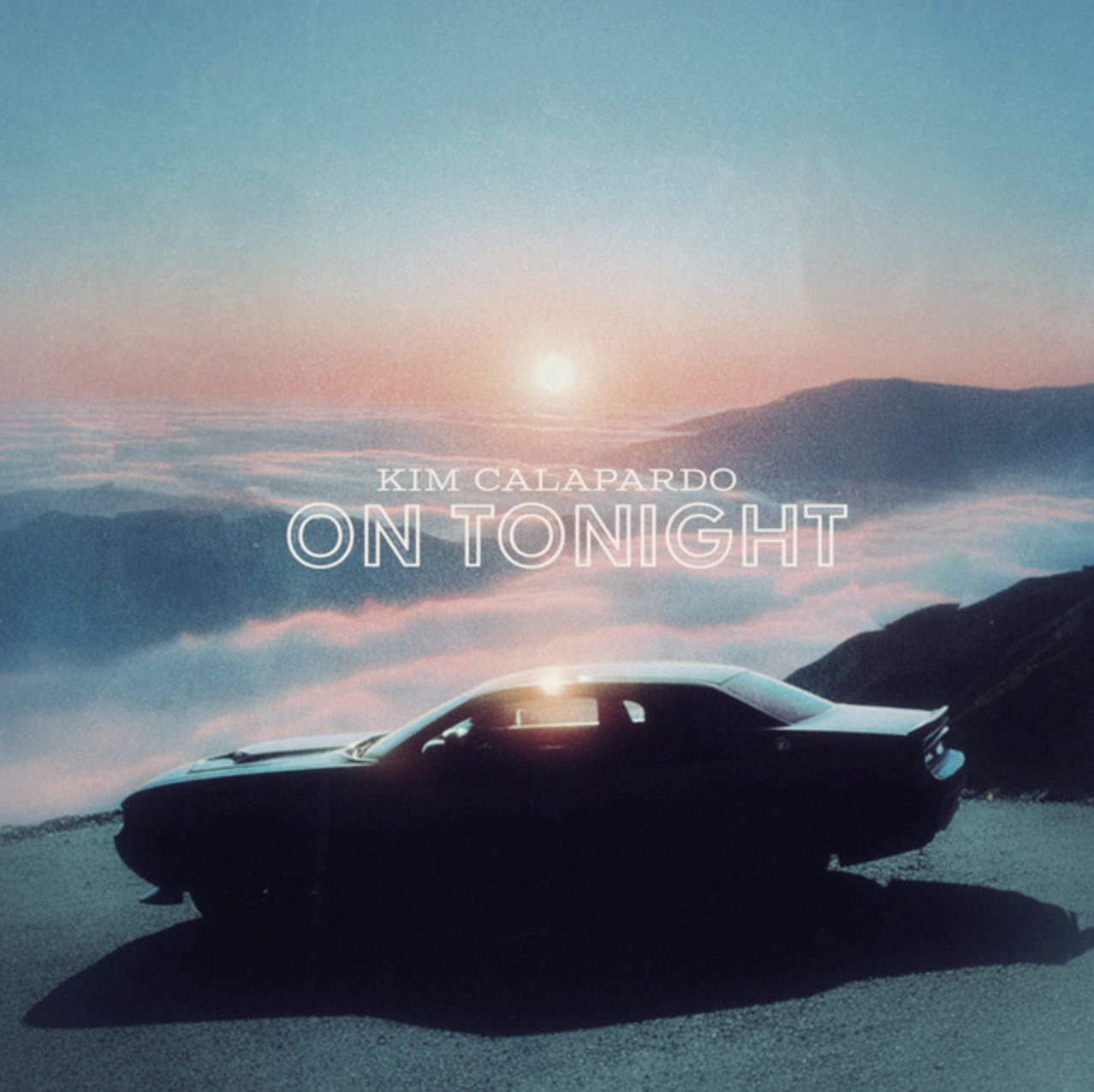 An album cover featuring a black sports car parked on a mountain road at sunset or sunrise, with a sky filled with soft pastel colors and clouds below the horizon. Text overlays include the artist's name Kim Calapardo and the title On Tonight.