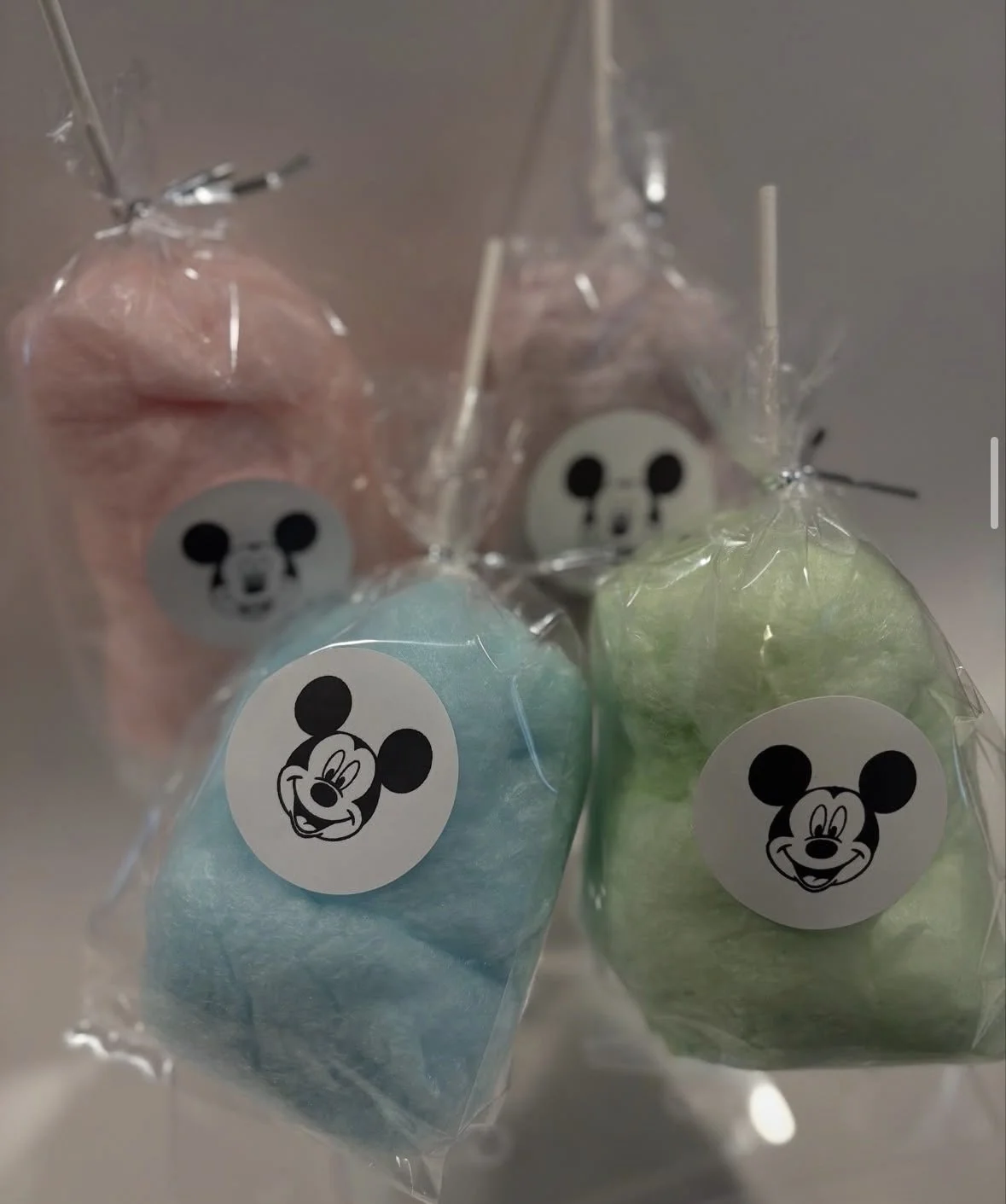 Colorful cotton candy bags with Mickey Mouse faces, one pink, one blue, and one green.