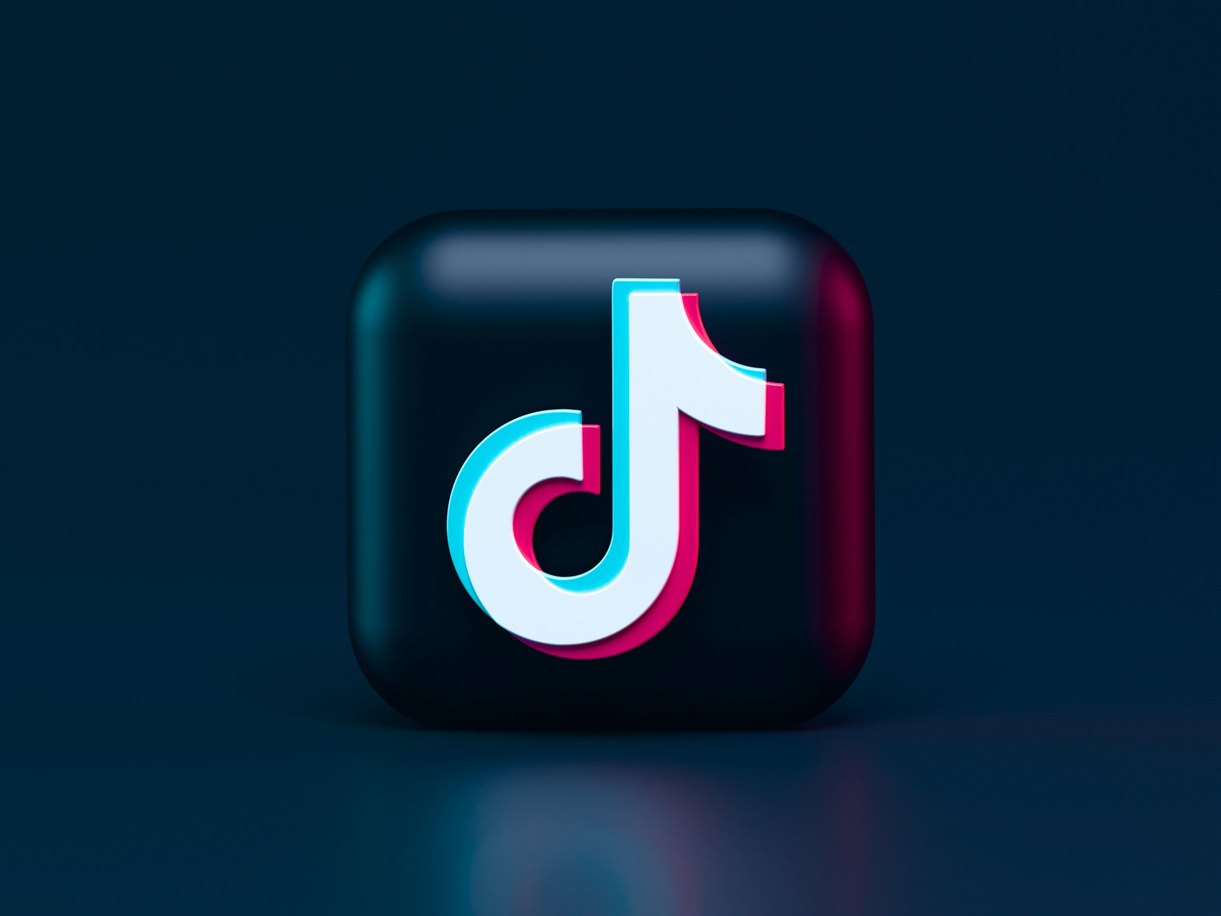 A 3D TikTok logo icon with a dark background.