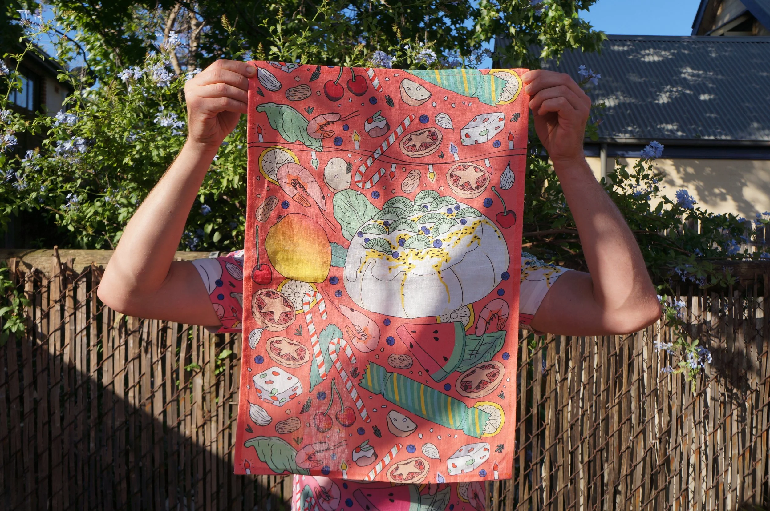 Photo of a person holding a tea towel picturing an Australian Christmas print on it by ANTIPASTEL, an illustrated textiles and homewares business created by Michaela Stone.