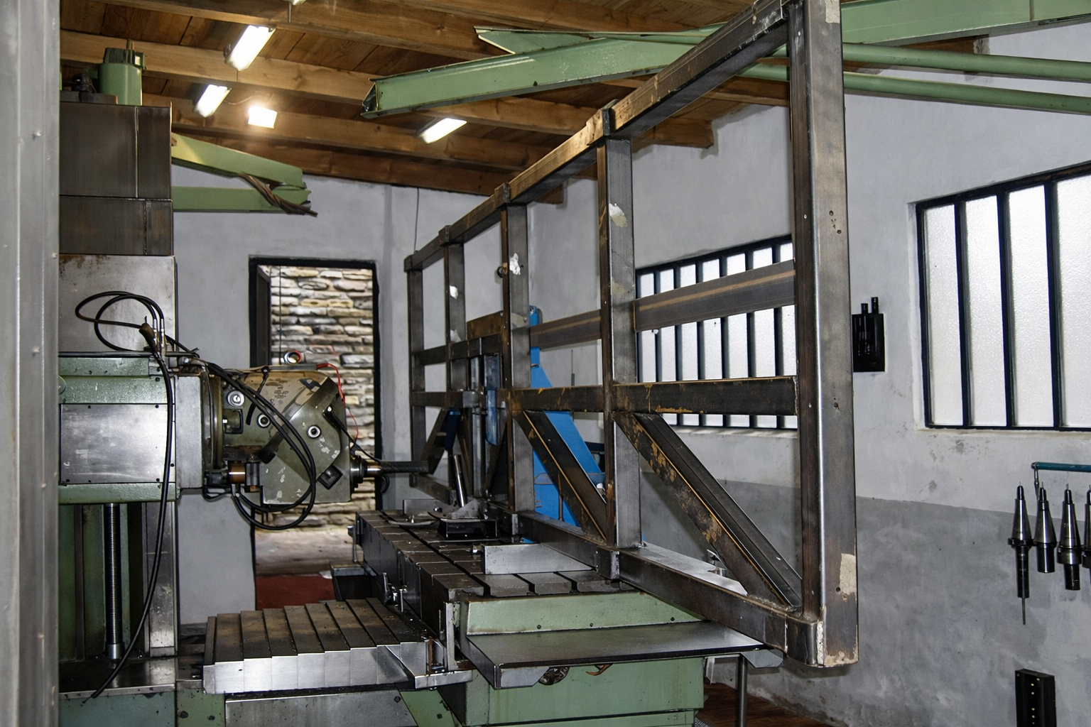 Macchina industriale in un laboratorio con struttura in metallo e strumenti di precisione, pareti di pietra sul retro e finestre con grate.