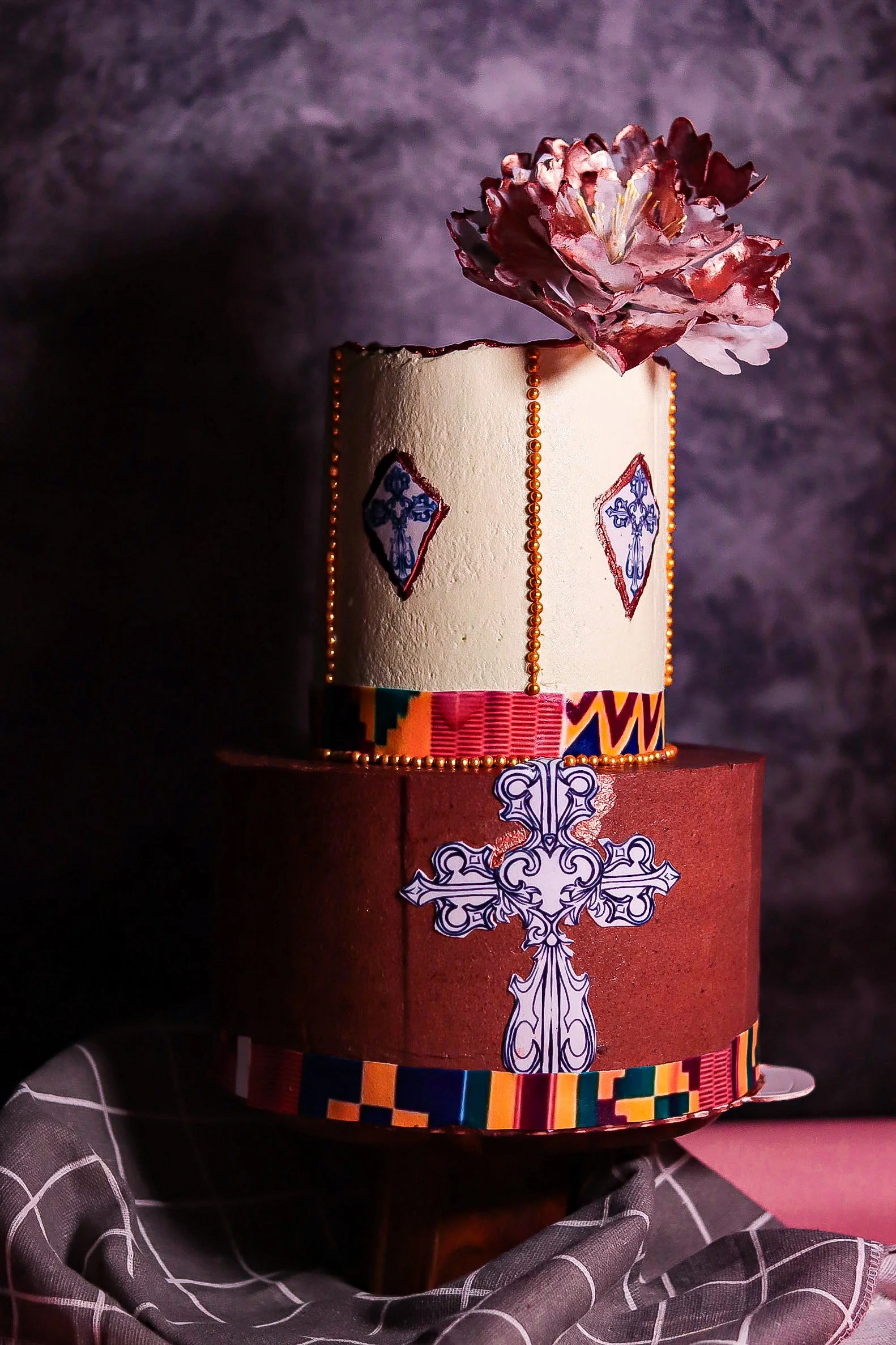 A two-tiered decorative cultural cake with edible printed images and buttercream filling and hand made wafer paper flowers.
