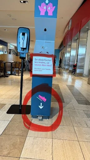 Hand-activated sensor button placed too high on a shopping mall pillar