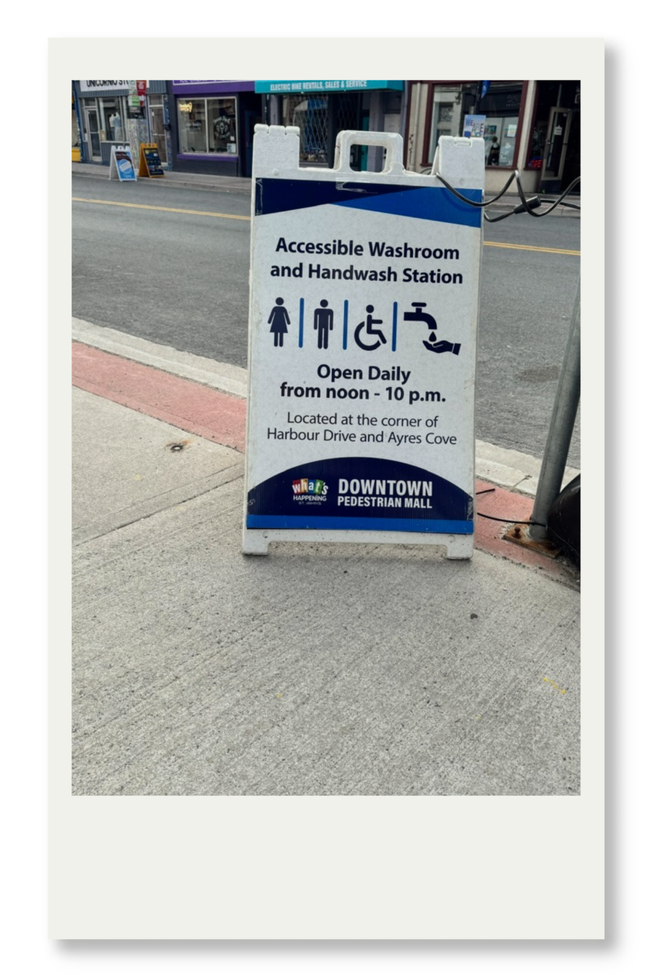 Sign advertising accessible washroom and handwash station in downtown pedestrian mall, open daily from noon to 10 p.m., located at Harbour Drive and Ayres Cove.