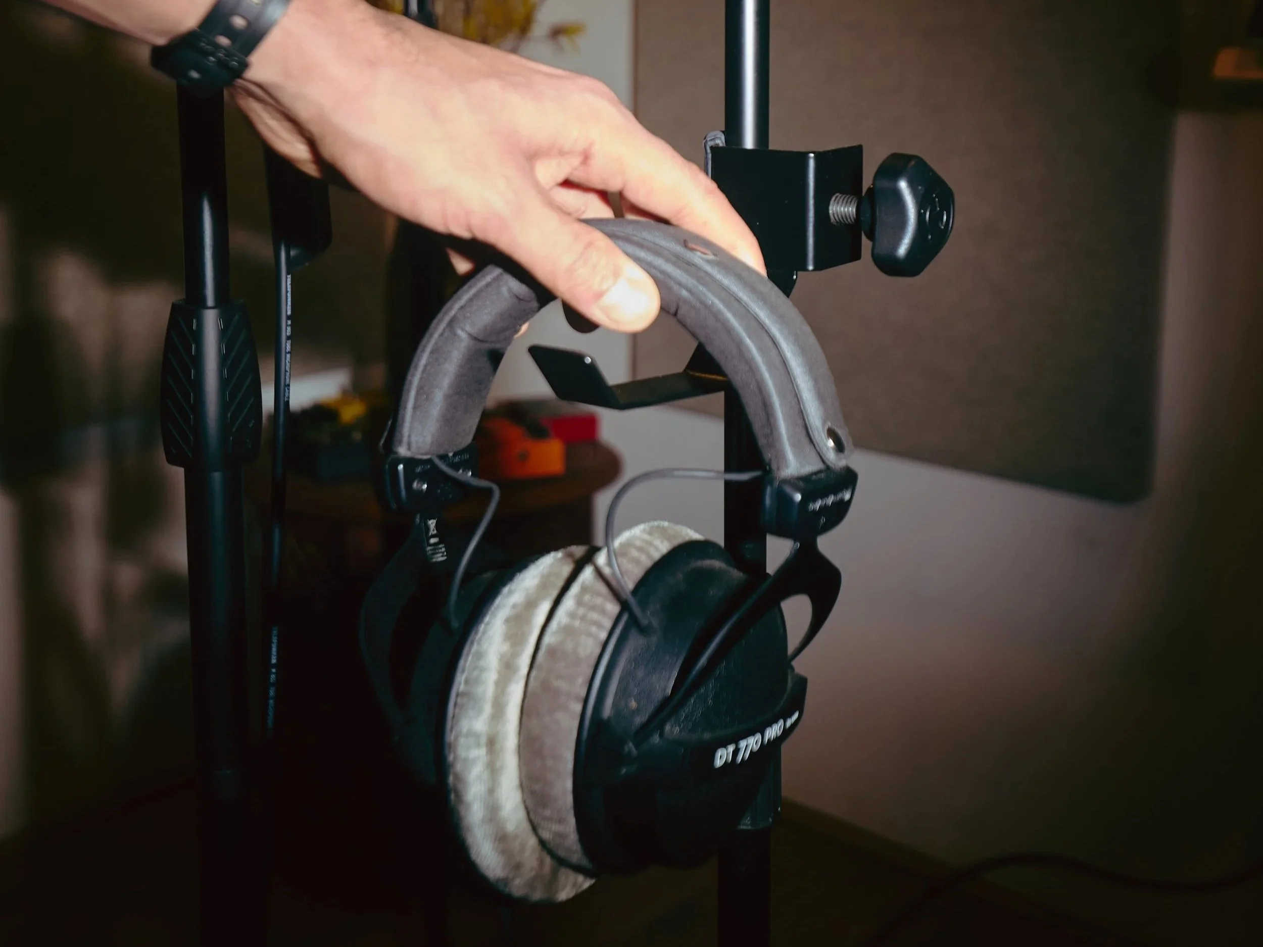 A person hanging up a pair of headphones on a headphone stand.