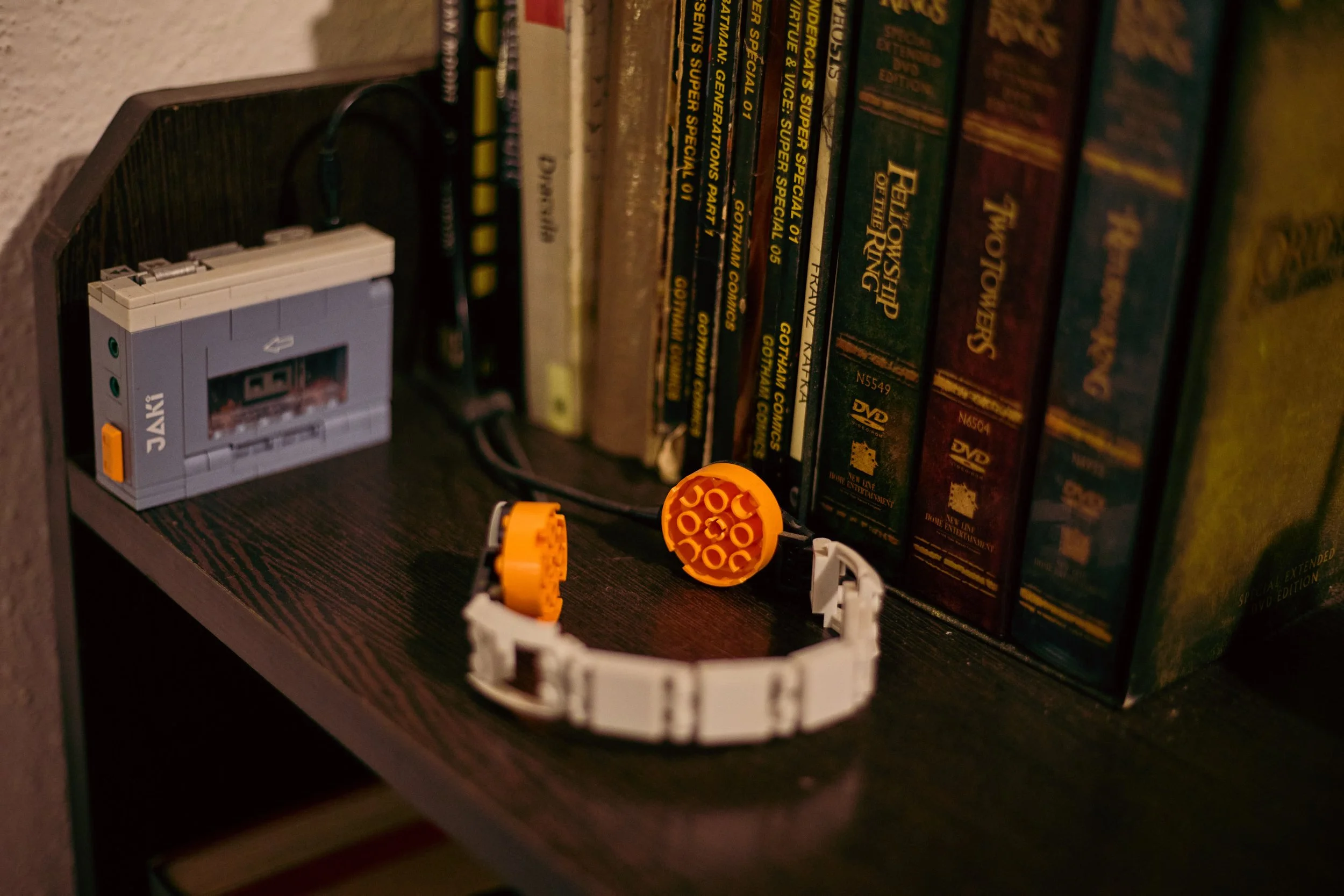A black bookshelf with books and a LEGO piece.