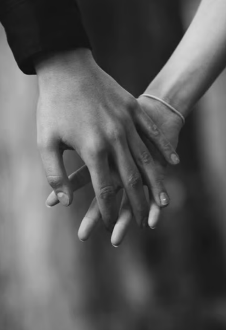 Deux mains qui se tiennent en arrière-plan flou, en noir et blanc.