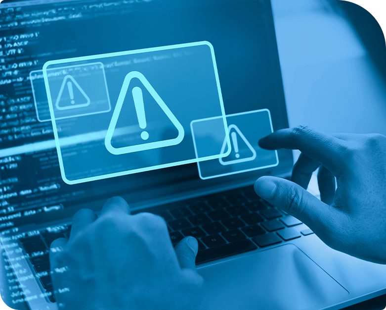 A person using a laptop with a digital warning alert displayed on the screen, indicating a system or security warning.