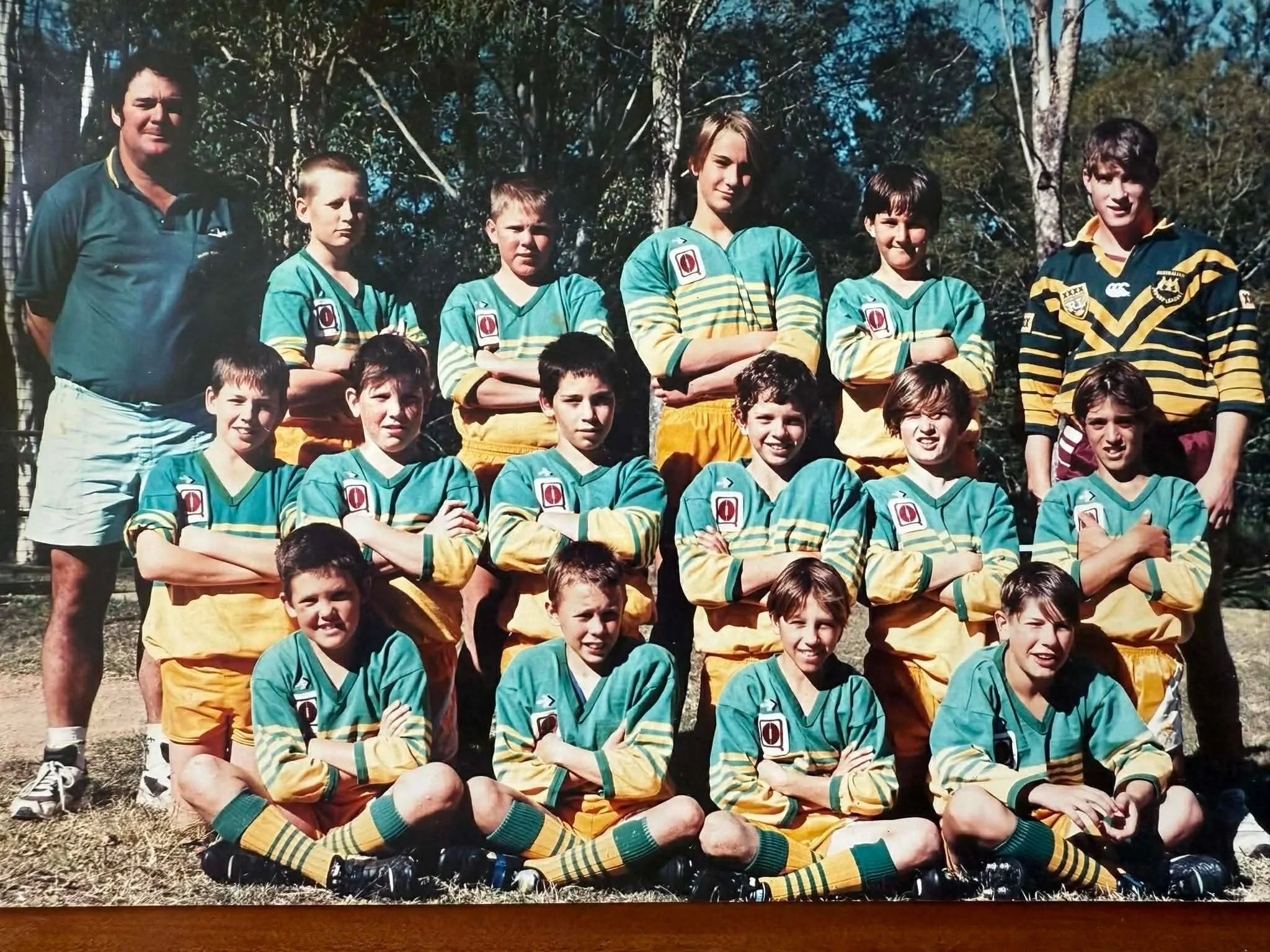 A youth rugby team with two adult coaches posing outdoors in a group photo.