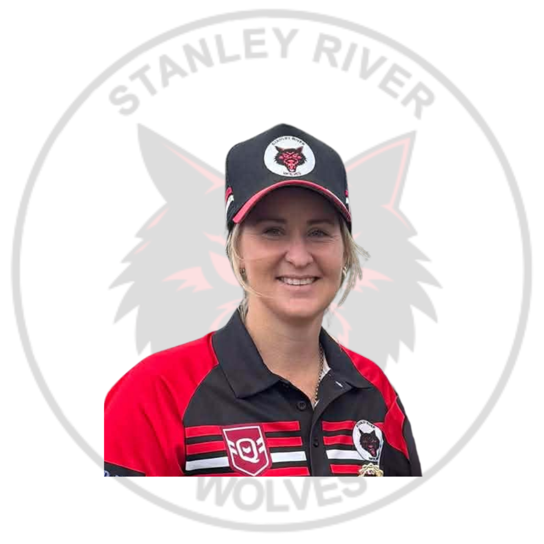 A woman in a black and red Harrisburg hockey team jacket and cap standing in front of a circular logo that reads 'Stanley River Wolves' with a wolf's head in the background.