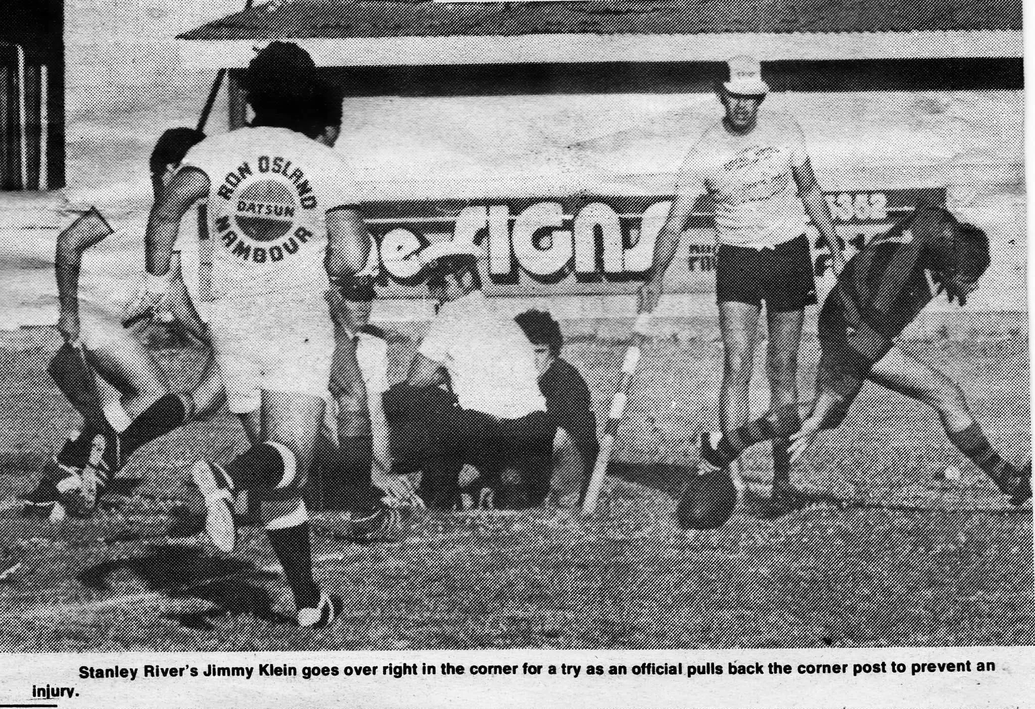 A black-and-white photo of a hockey game where a player is falling on the ice near the goal, with several officials and players around him. The scene shows a close-up of the action with the goalpost, and a caption below reads: "Stanley River's Jimmy 