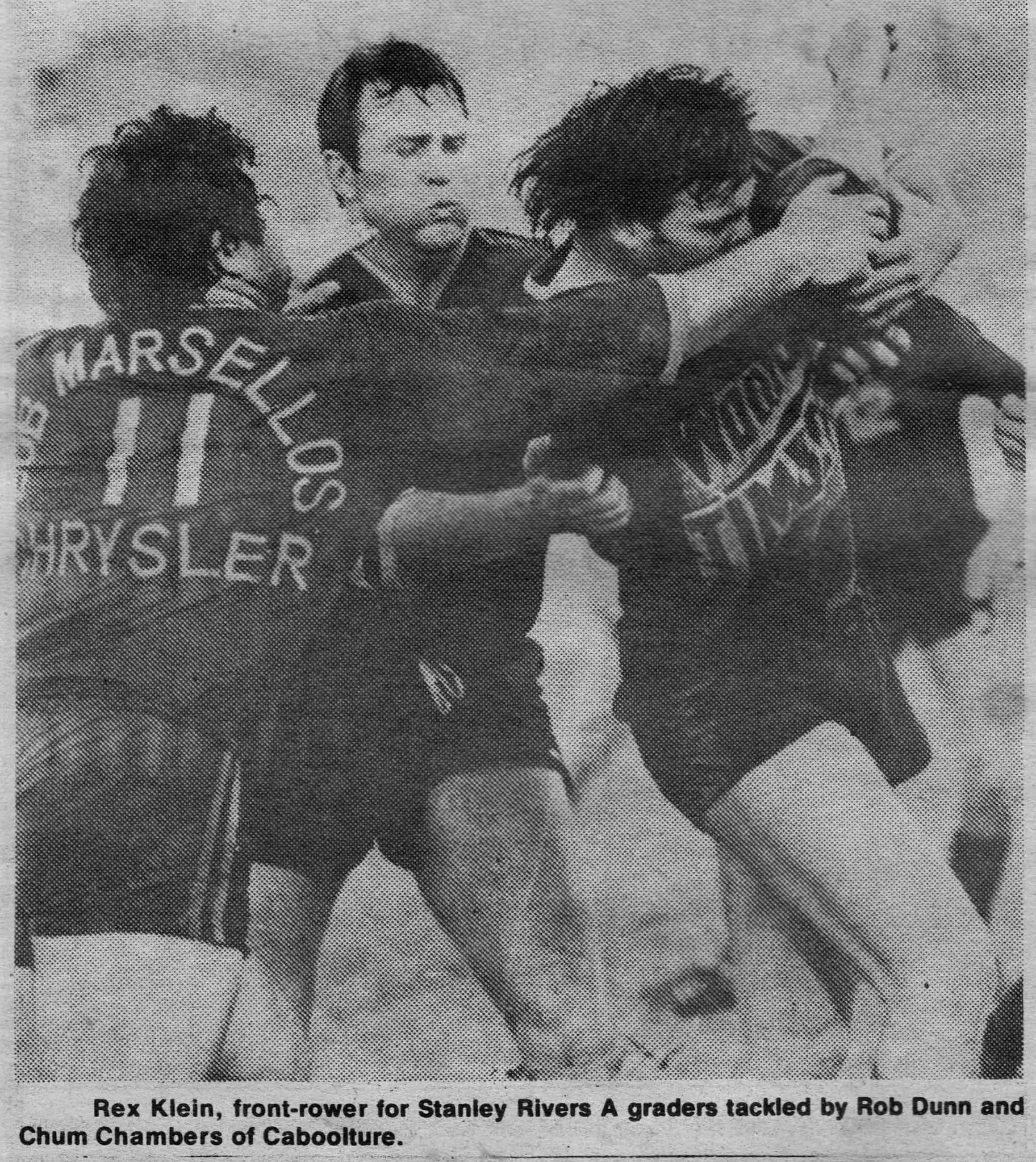 Black and white photo of rugby players, with one wearing jersey number 11 labeled Marquisel, engaging in a tackle on a player from Stanley Rivers. The action occurs during a rugby game.