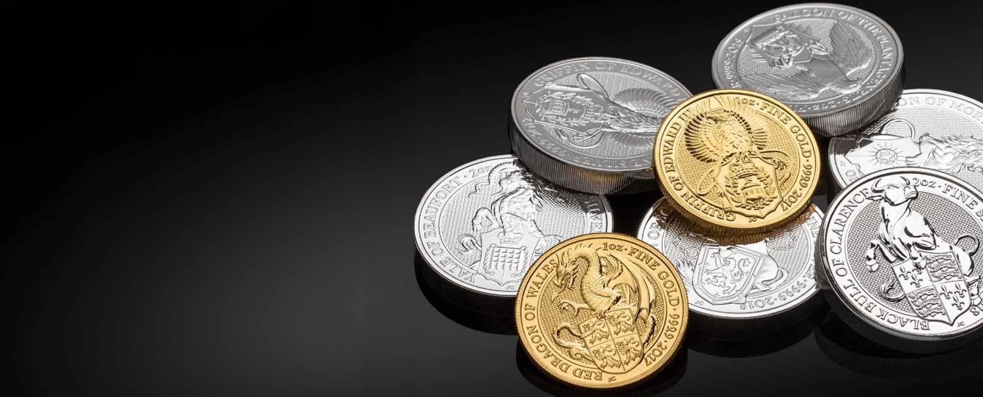 A collection of silver and gold coins of various designs and denominations on a black surface.