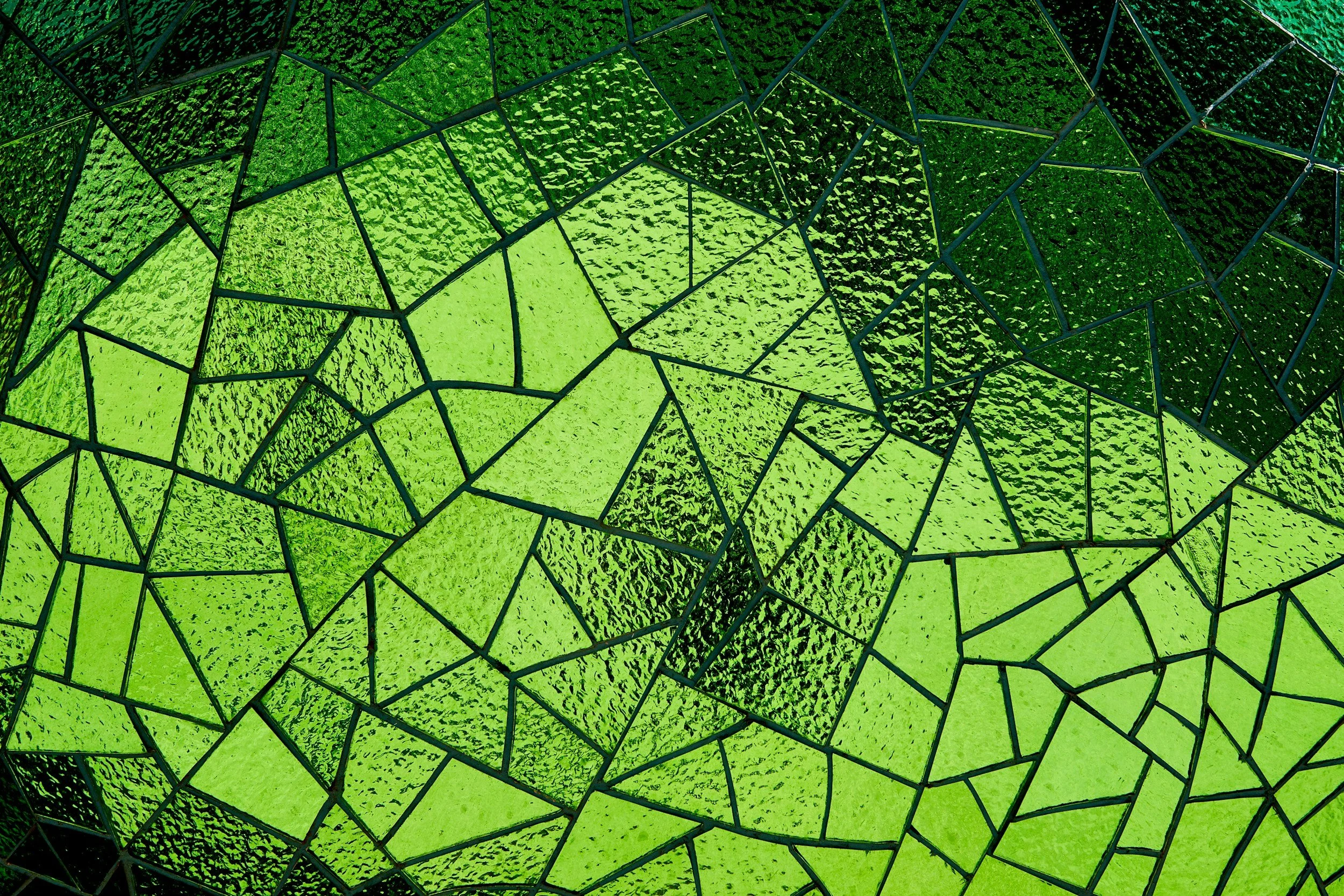 Close-up of a green stained glass mosaic with irregular geometric shapes separated by dark lines.