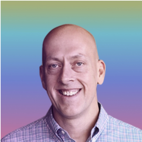 A smiling man with a bald head and light blue eyes, wearing a checkered shirt, against a colorful gradient background.