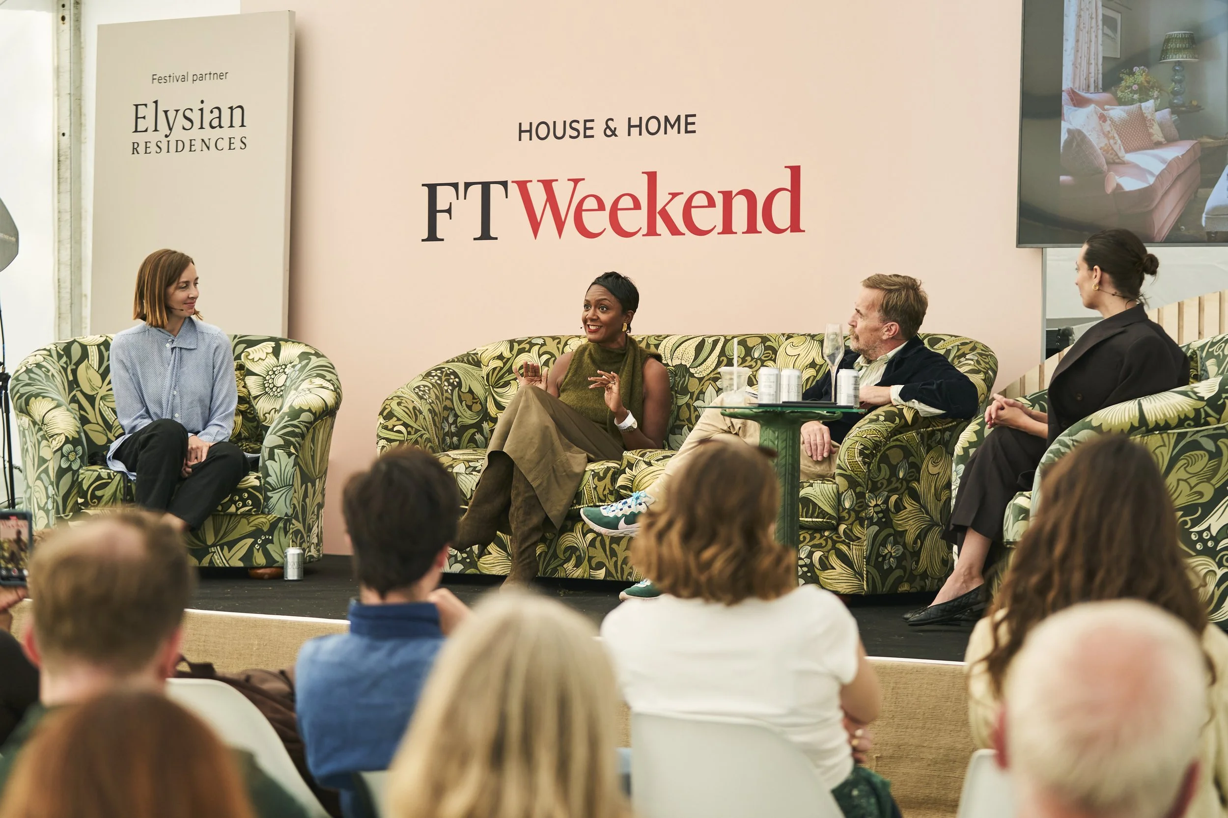Panel discussion at the FT Weekend House & Home event, with four people sitting on a stage in front of an audience. A large sign behind them reads 'FT Weekend' and 'House & Home'. The panel includes two women and two men, seated on patterned sofa chairs, with a small green table holding drinks.