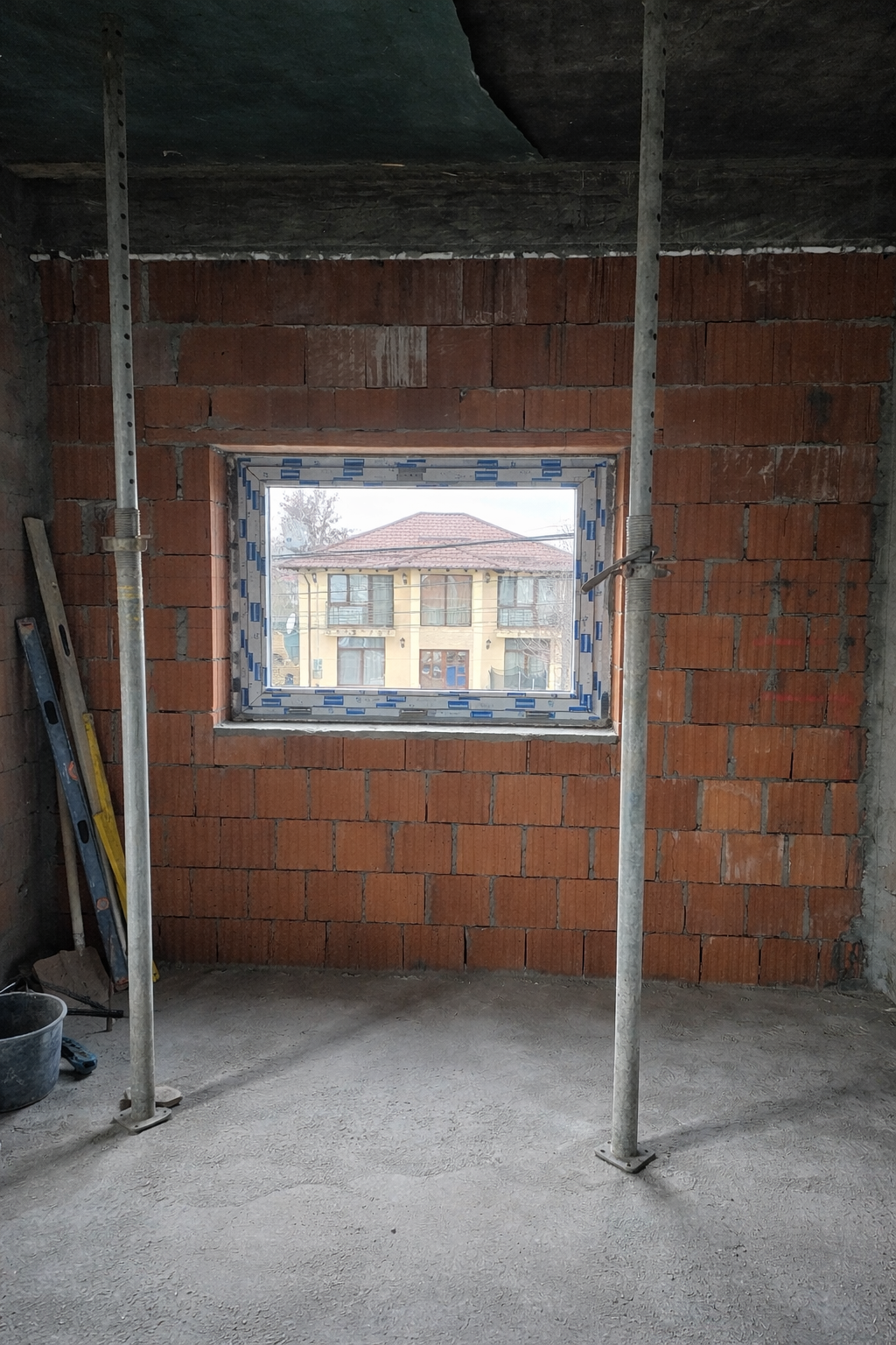 Interior of a building under construction with a window and exposed bricks.