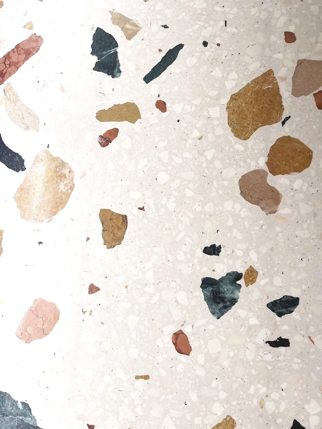 Bodenbelag mit verschiedenen bunten Splittern und Steinen auf hellem Untergrund.