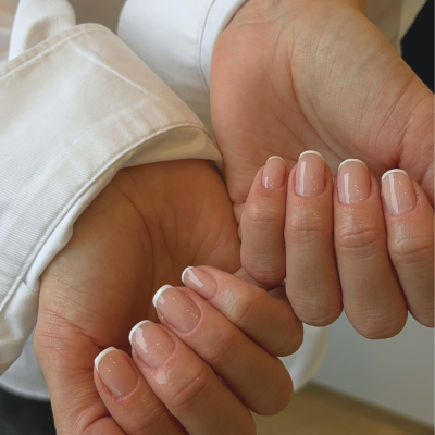 Close-up of hands with well-manicured nails, and a white shirt sleeve visible.