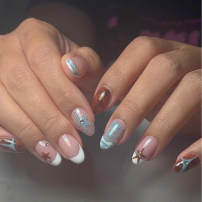 Close-up of hands with decorated fingernails featuring pastel colors, stars, and abstract designs.