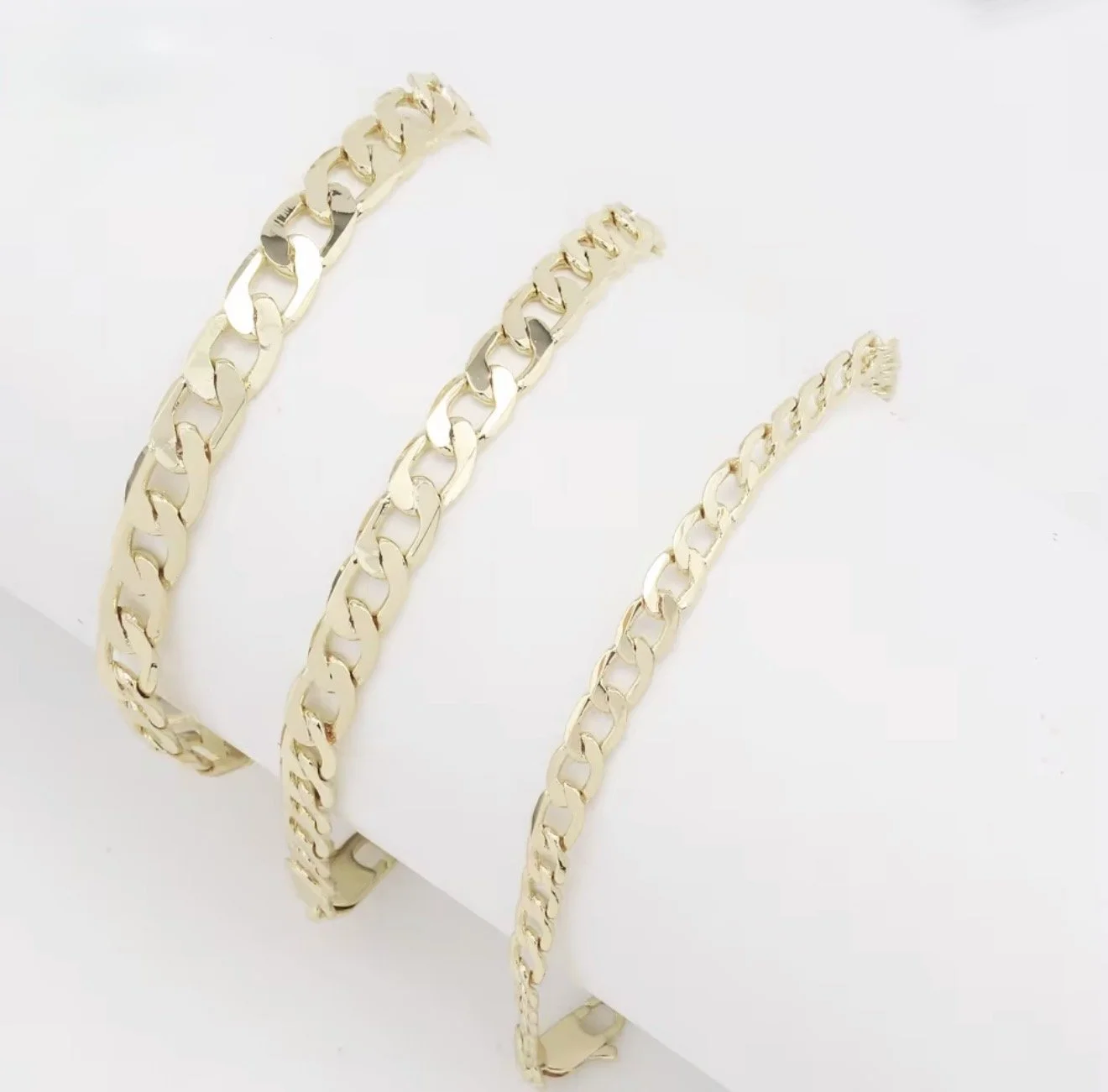 Three gold chain necklaces of varying thicknesses displayed on a white background.