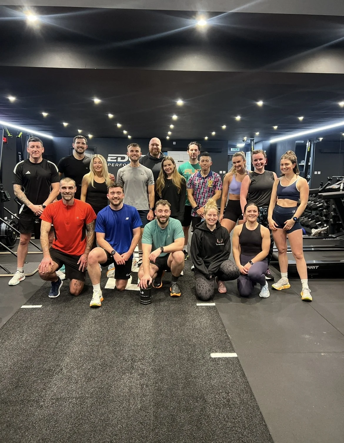 Group of people in workout clothes posing in a gym.