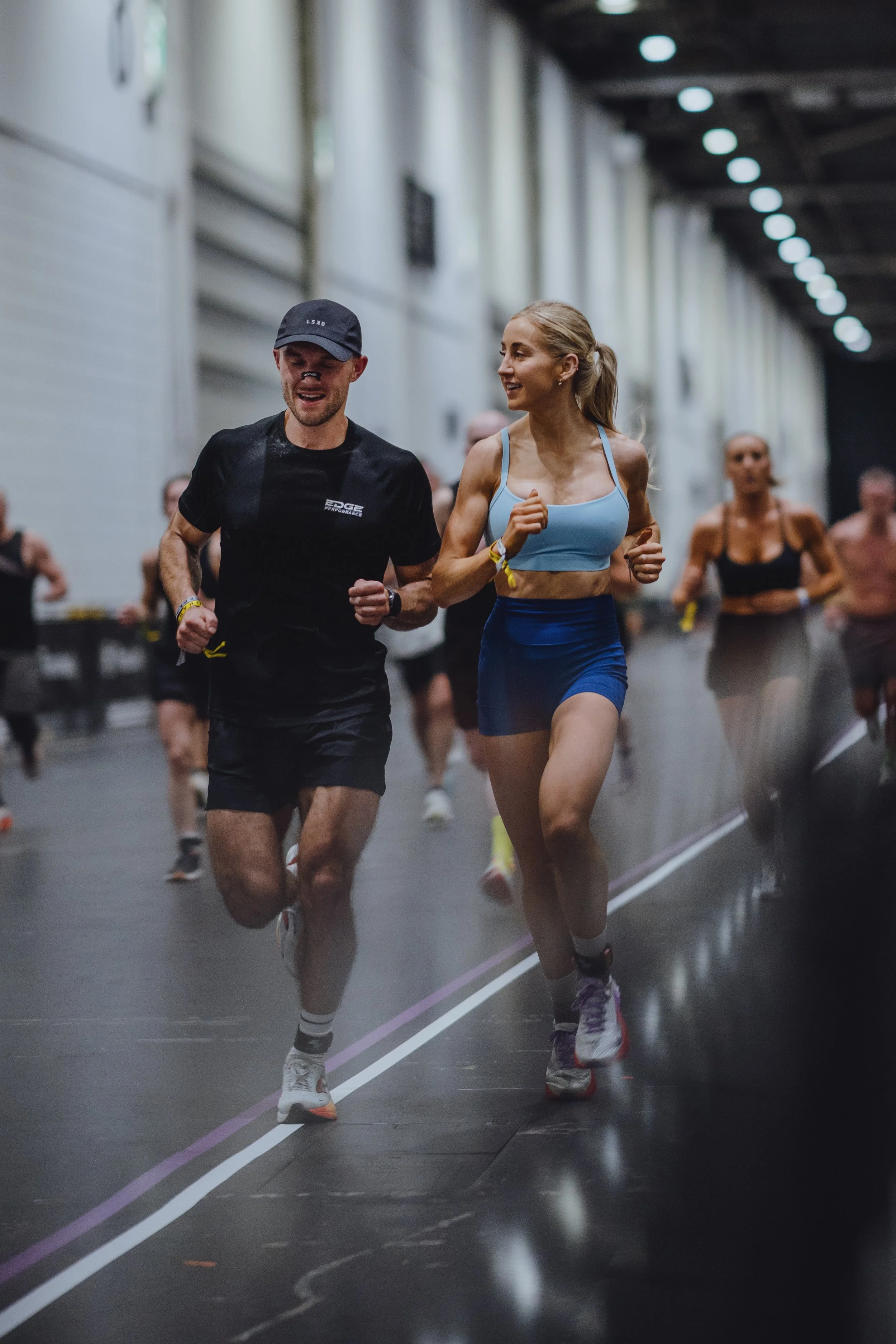 People running inside a large indoor track or sports facility.