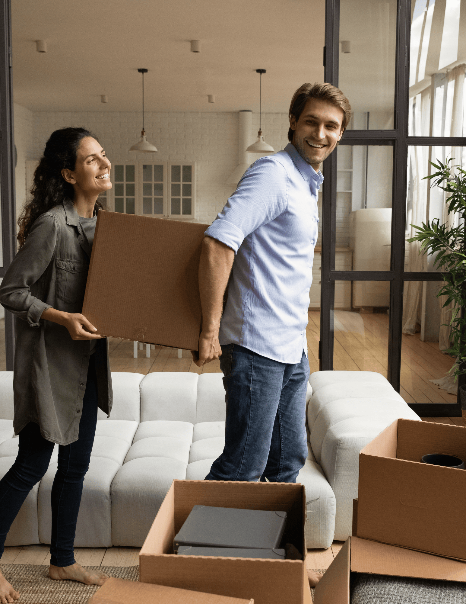 Two people moving boxes in a living room, smiling and working together.