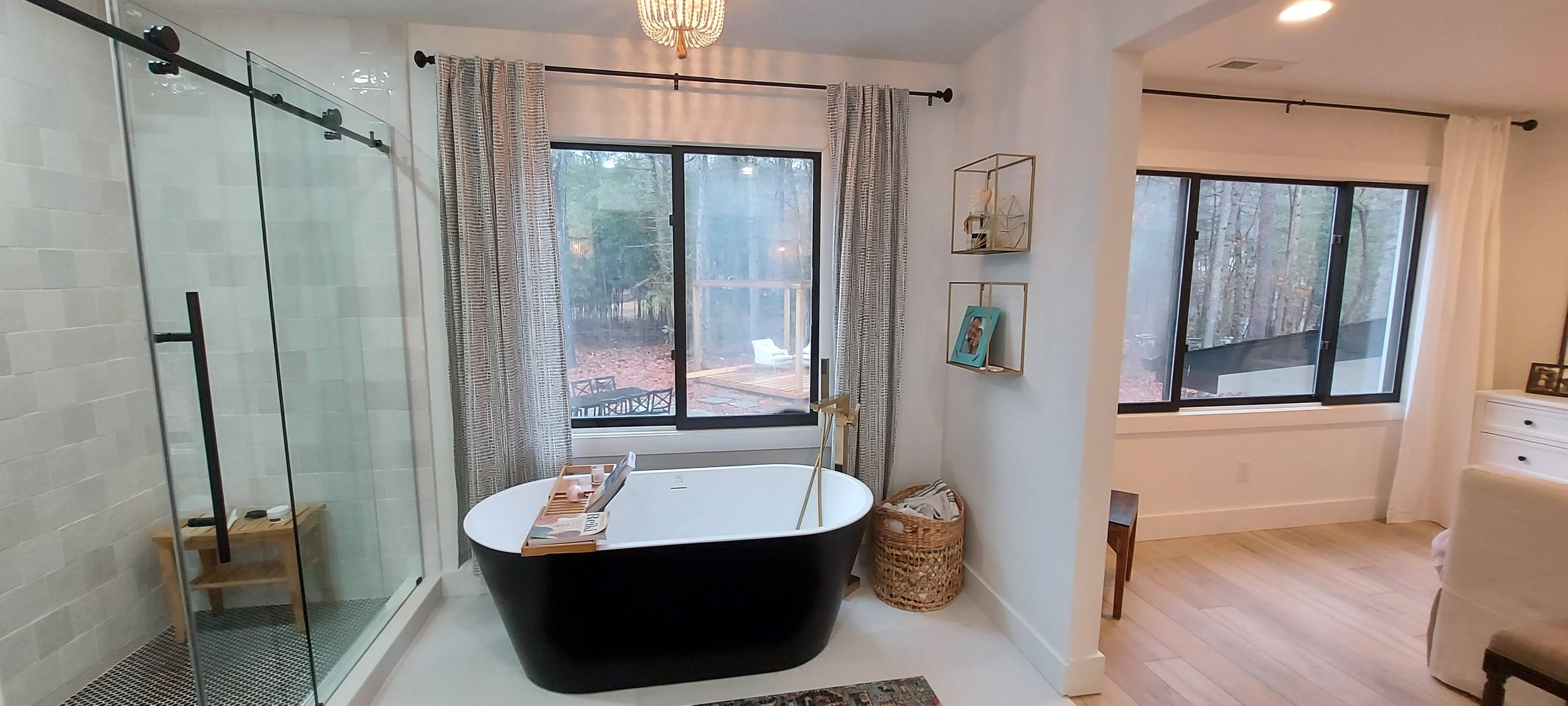 deep soaker tub in a renovated bathroom with classic black and white accents and gold finish hardware