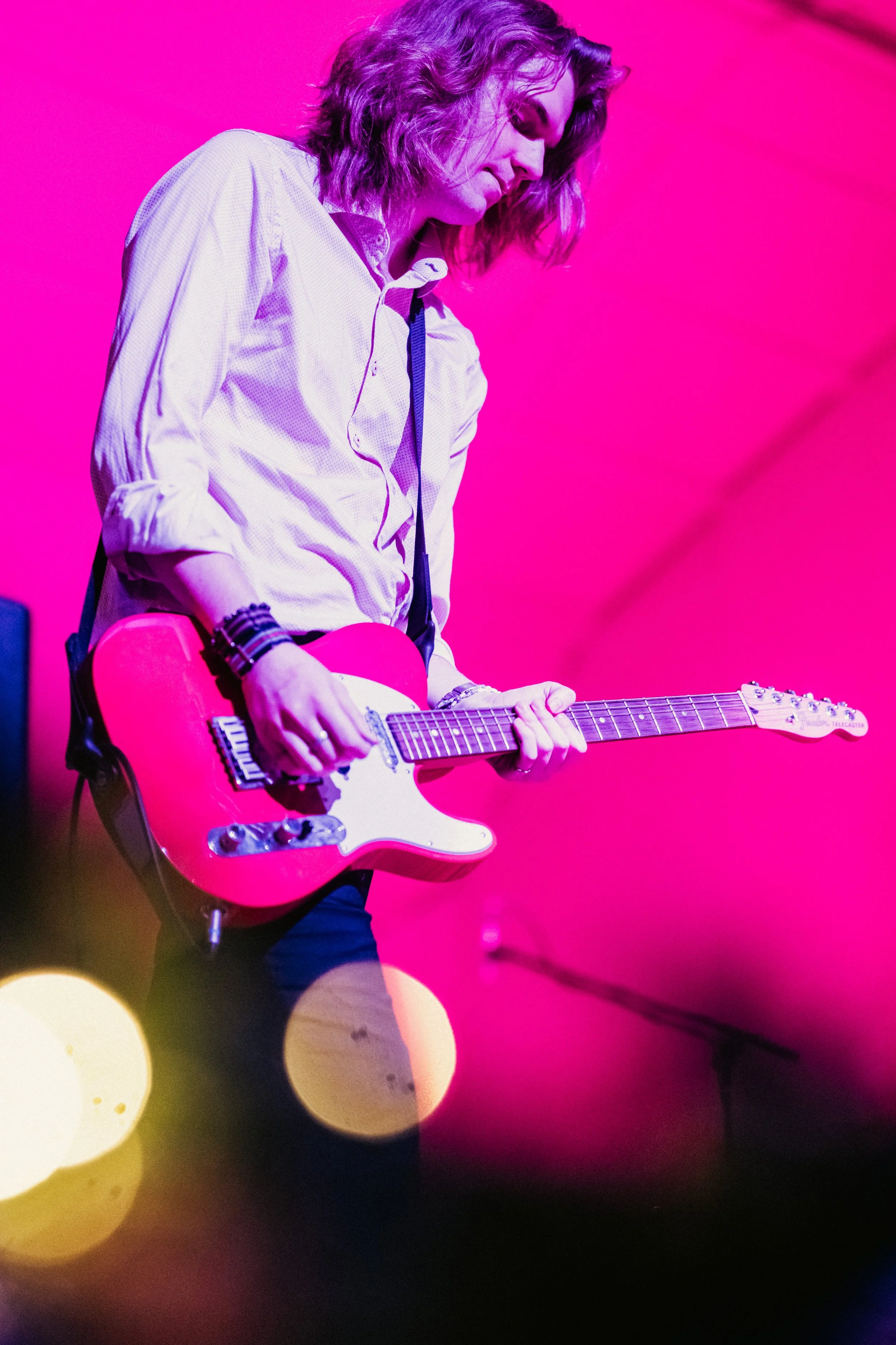 Nuori nainen soittaa pinkillä sähkökitaralla pinkillä taustalla.