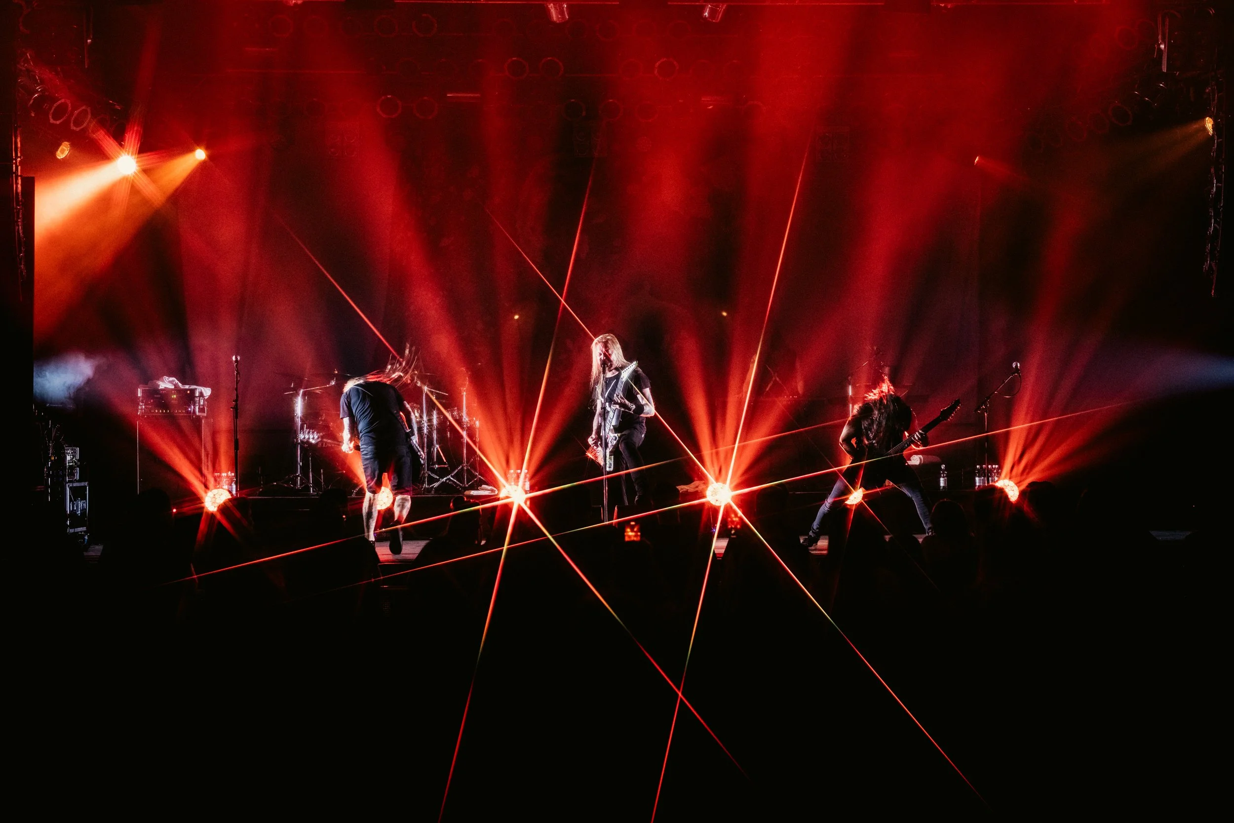 Live rock-konsertti, jossa yhtye esiintyy lavalla punaisissa valoissa ja valokeilassa