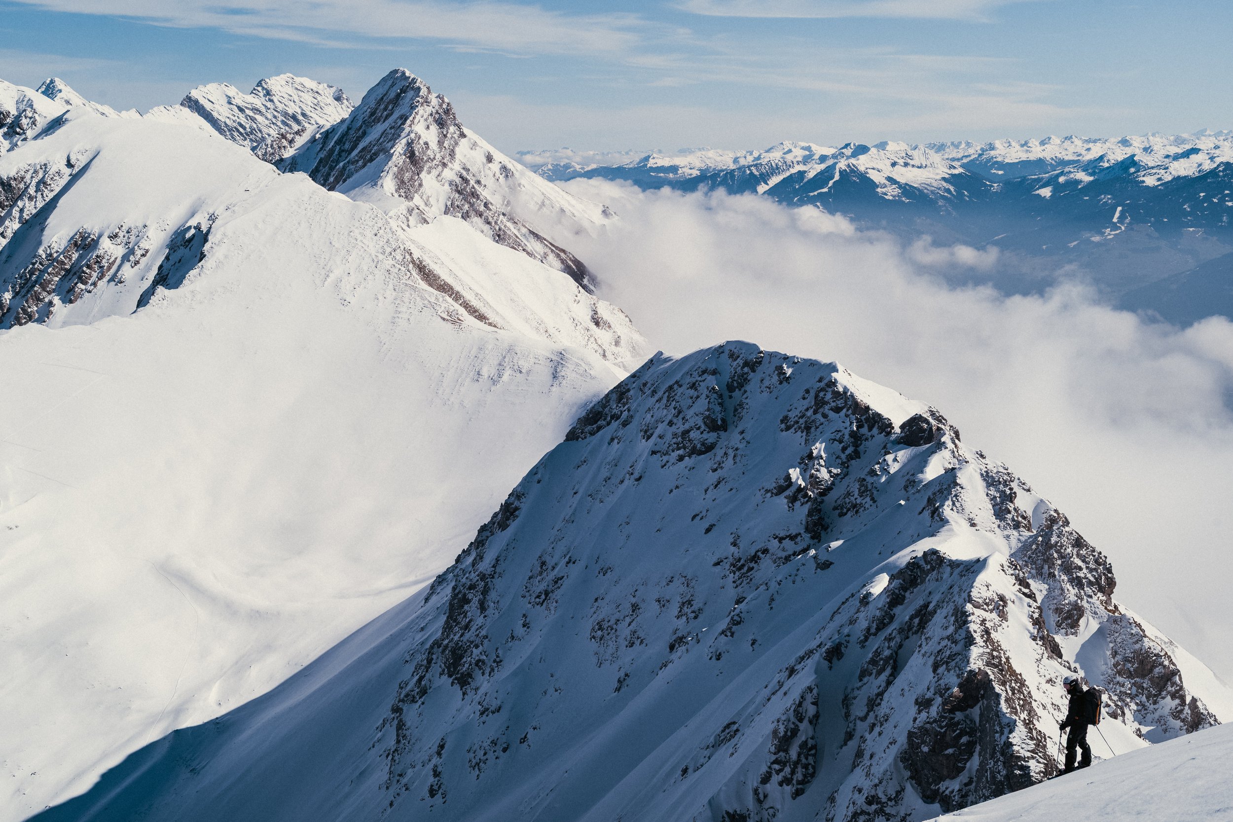 Vuoristomaisema lumiset vuoret ja pilvet taivaalla, kiipeilijä vuorenrinteellä