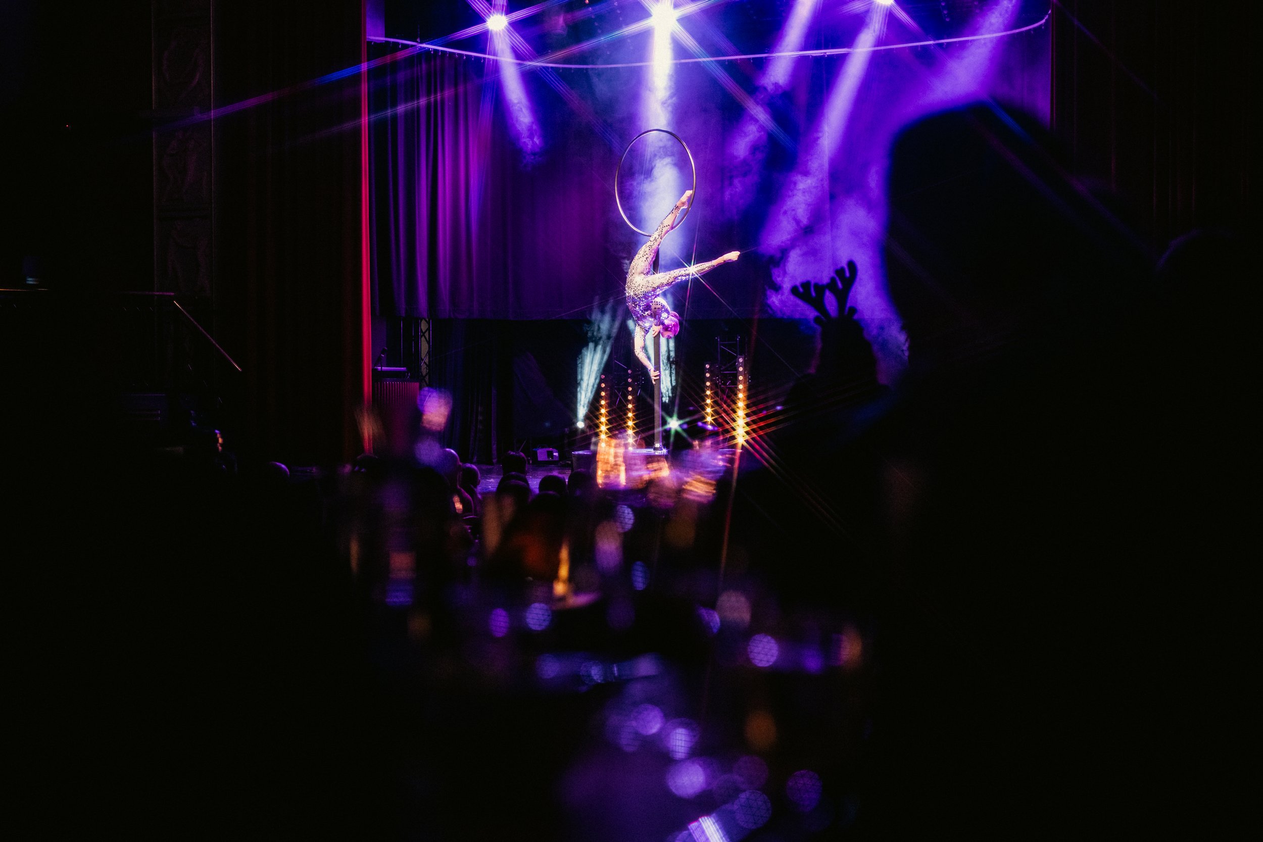 Akrobaattinen esitys esiintymislavalla, valaistuksella ja savukoneella luoden taianomaista ilmettä.